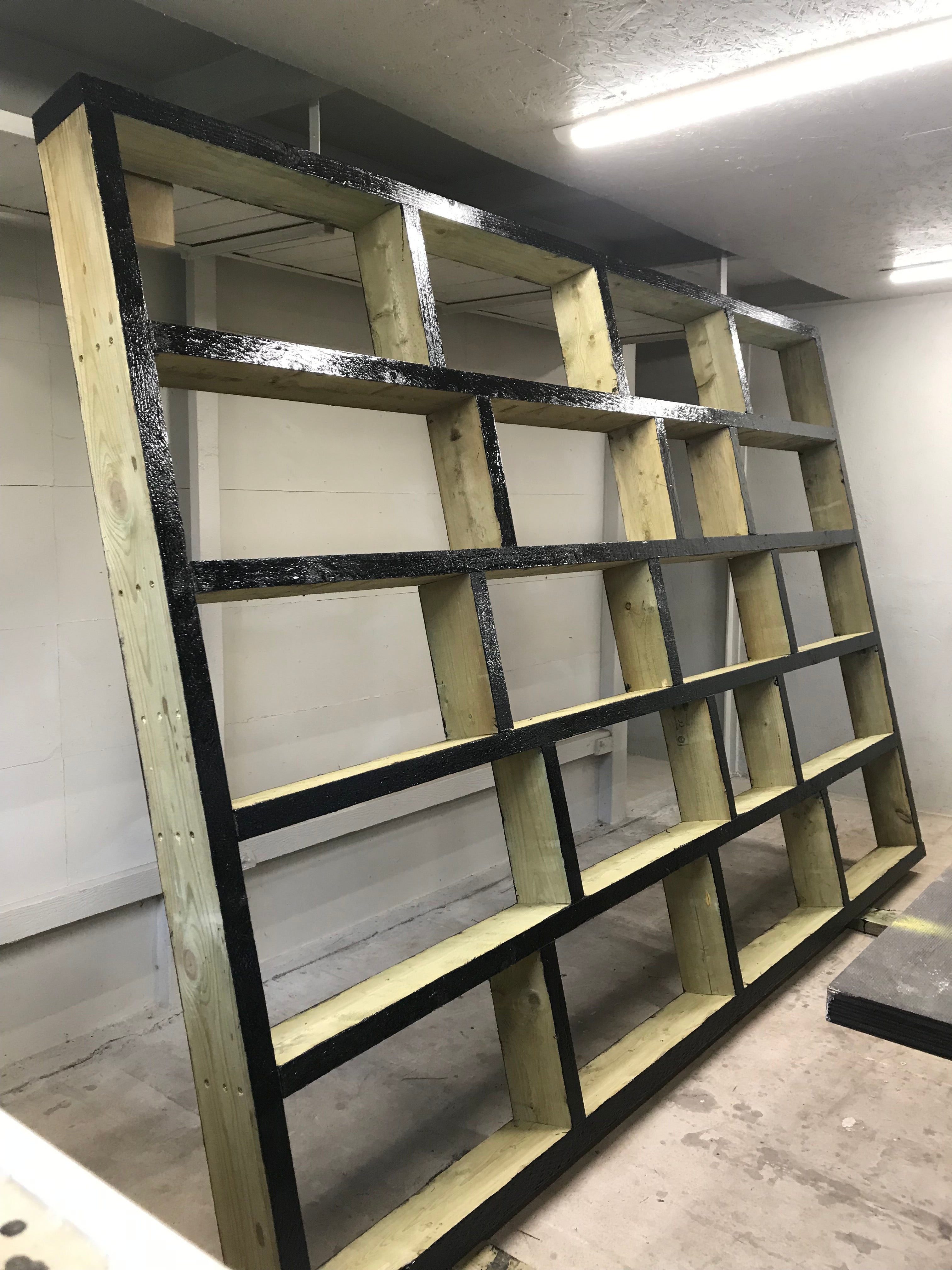 Wooden frame with multiple square compartments on a concrete floor.