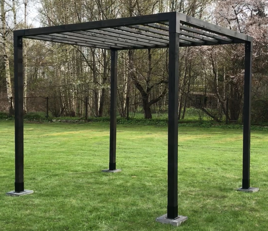 Black metal pergola structure on a grassy area with trees in the background