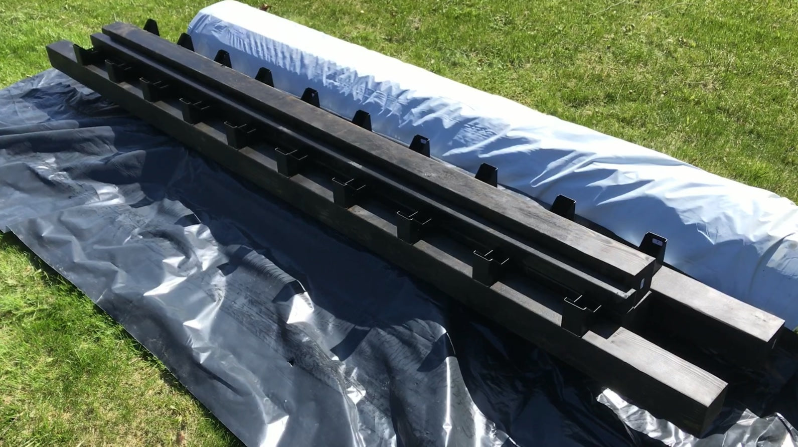 Black metal rack on a blue tarp with grass in the background