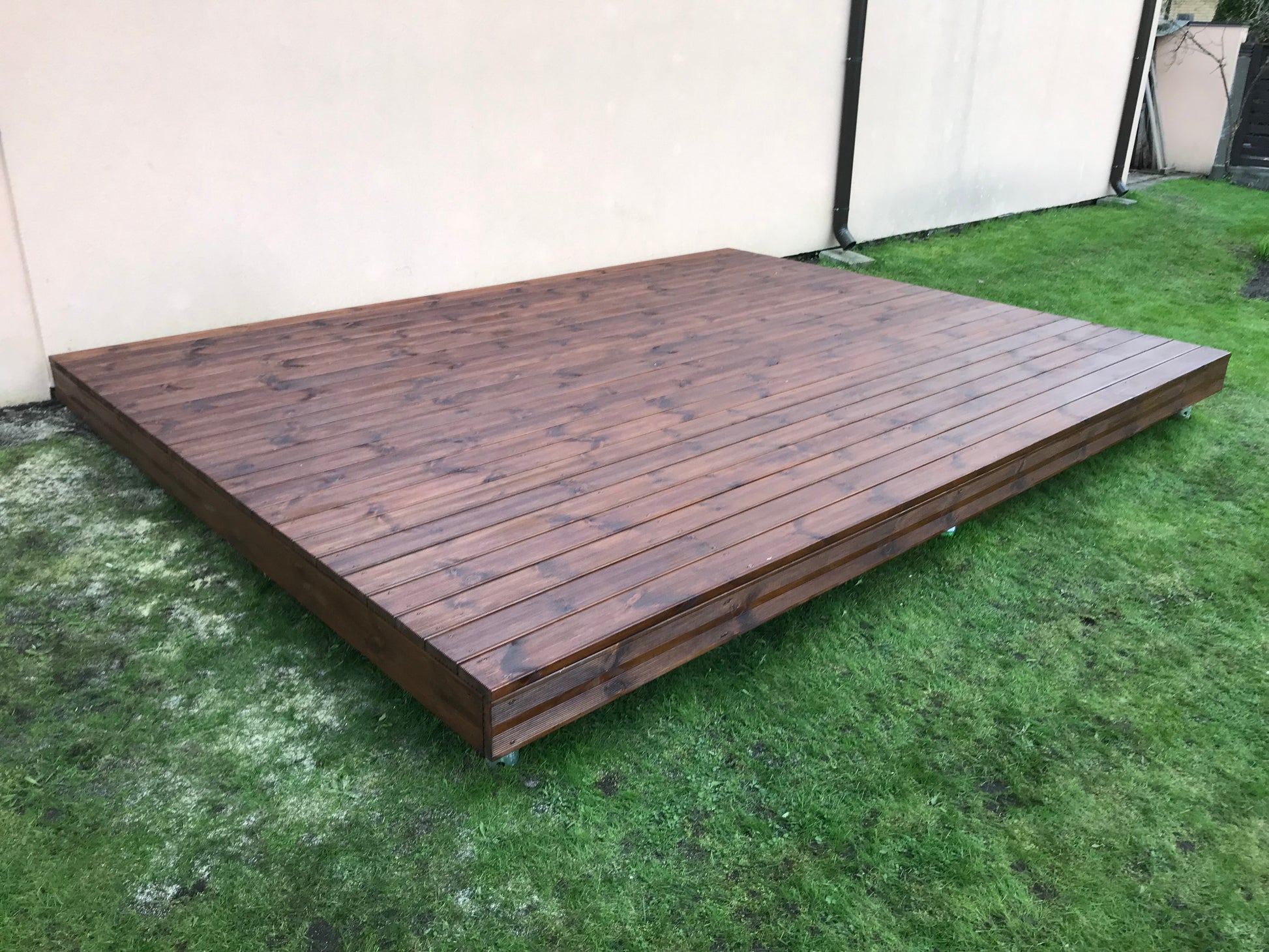 Wooden deck on grass with a white wall background