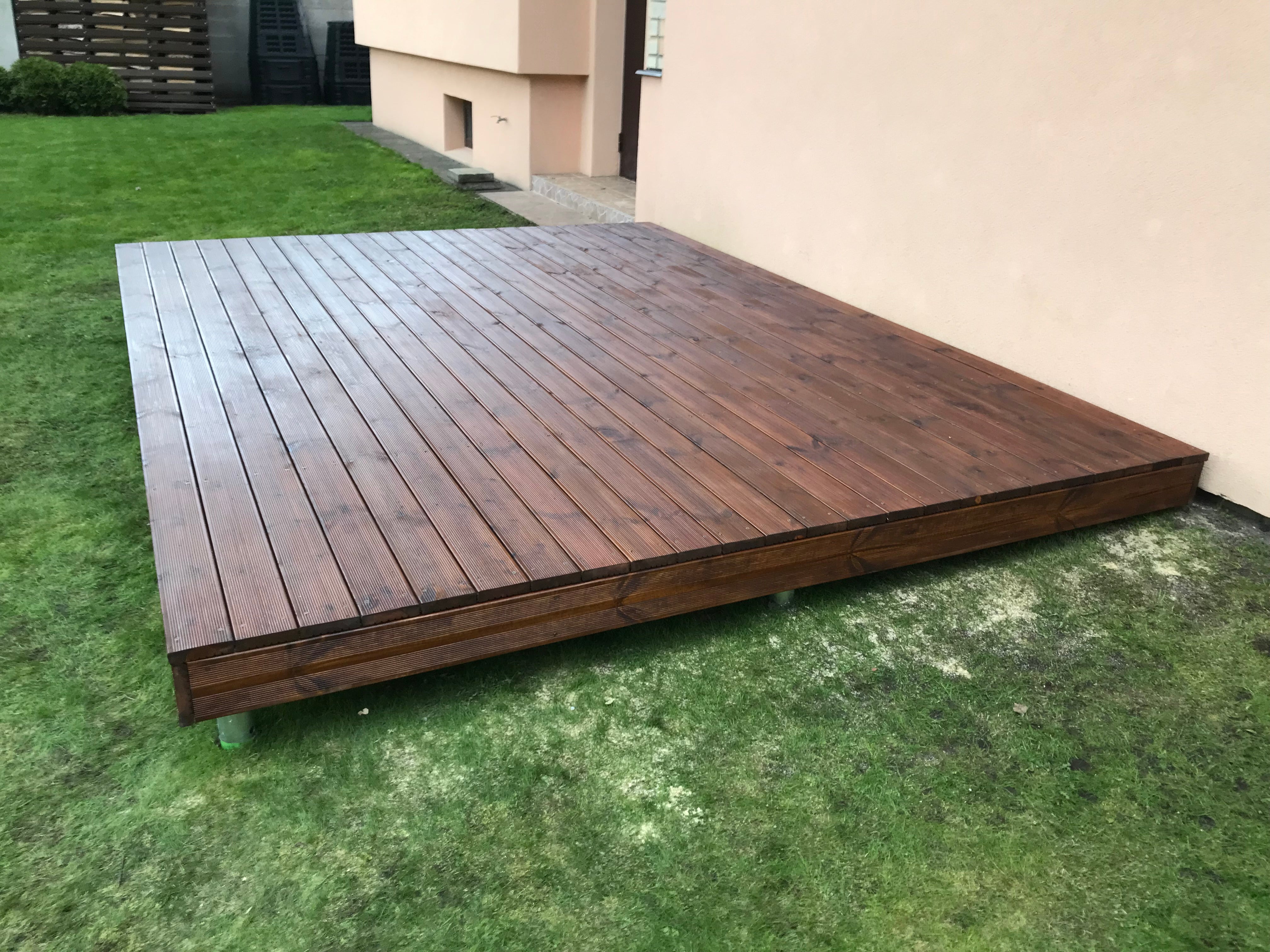 Wooden deck on grass with a building in the background