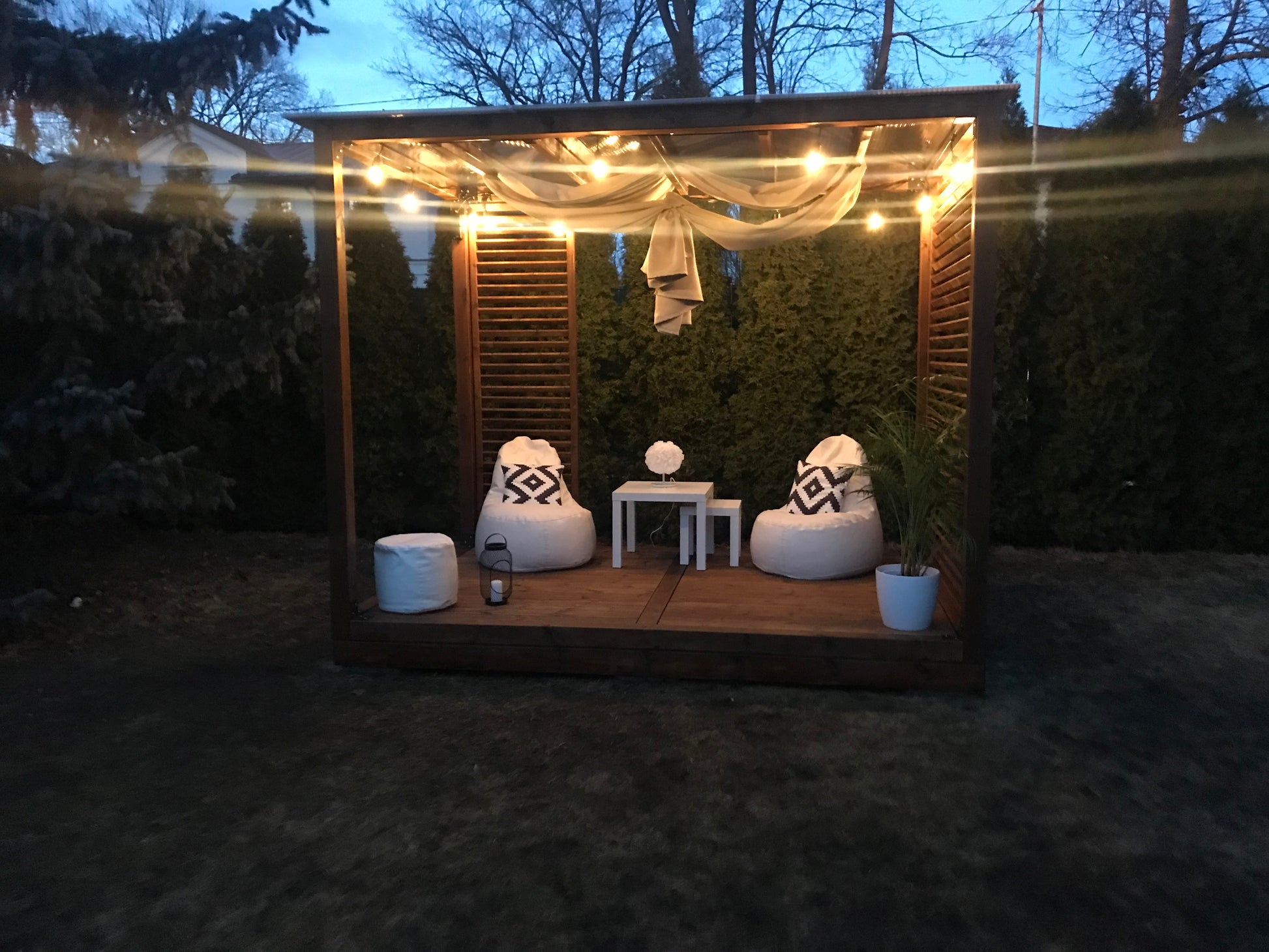 Outdoor seating area with two bean bags, a small table, and string lights in a garden setting.