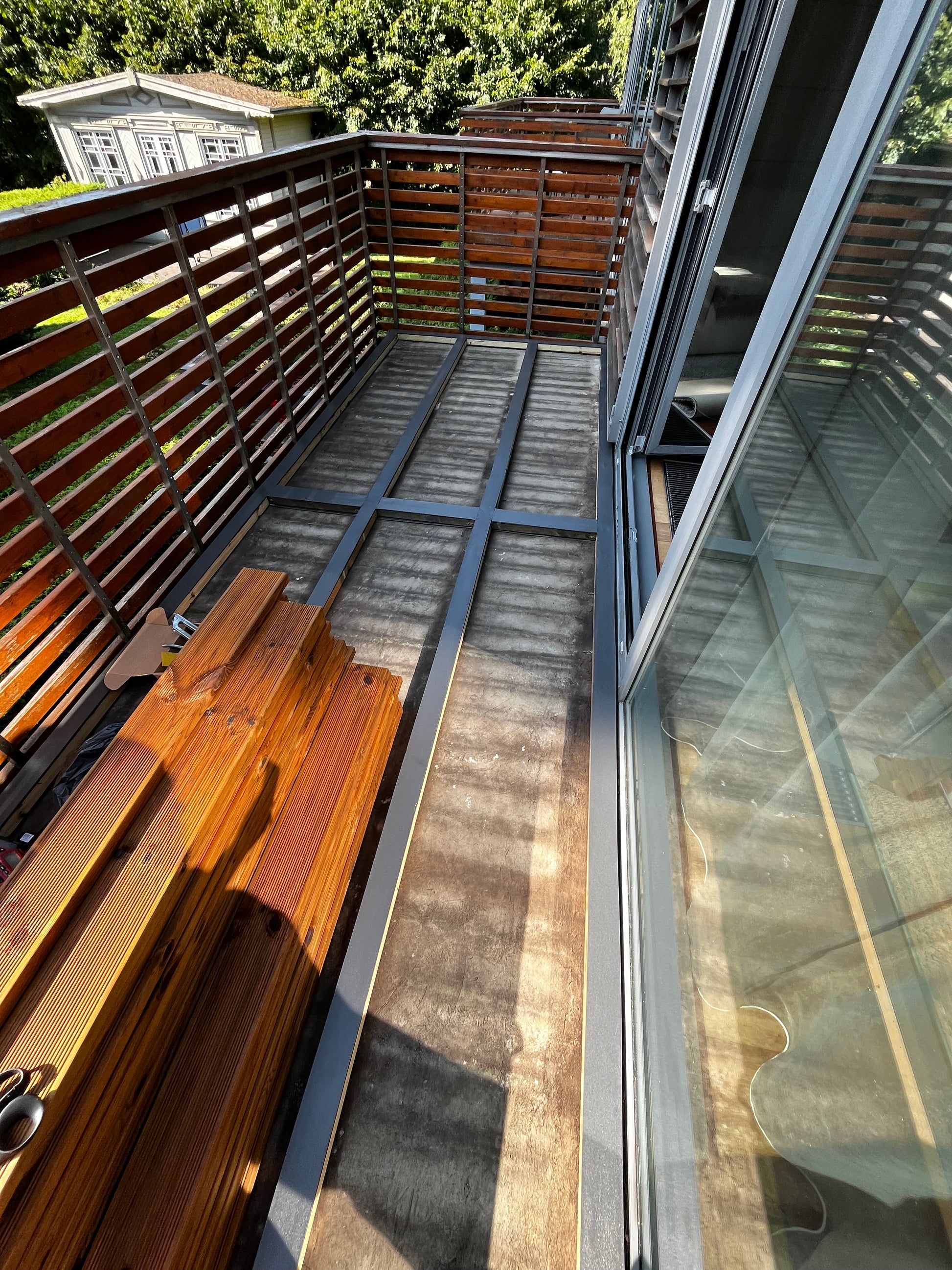 Wooden deck chairs on a balcony with a glass wall