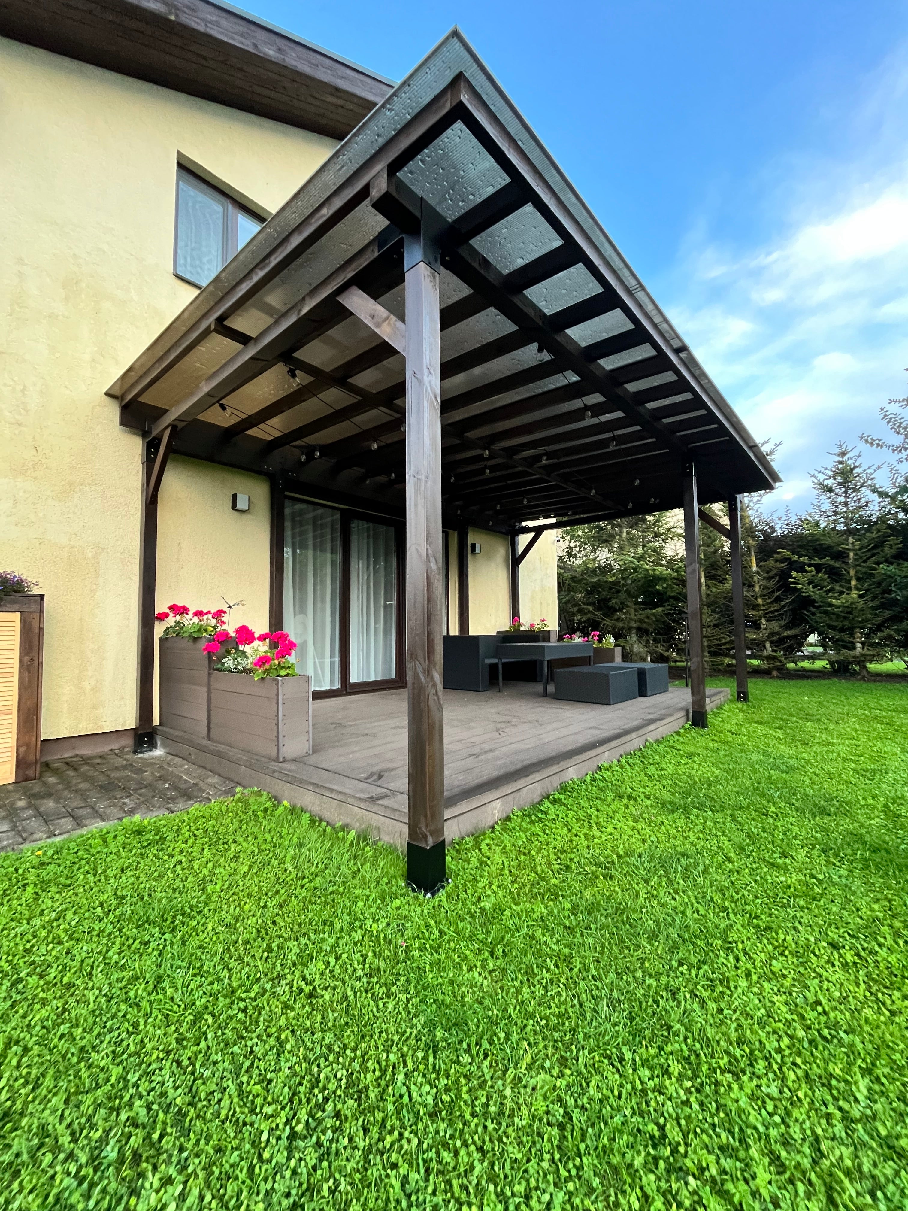 Outdoor patio area with a wooden deck and grassy lawn under a clear blue sky.