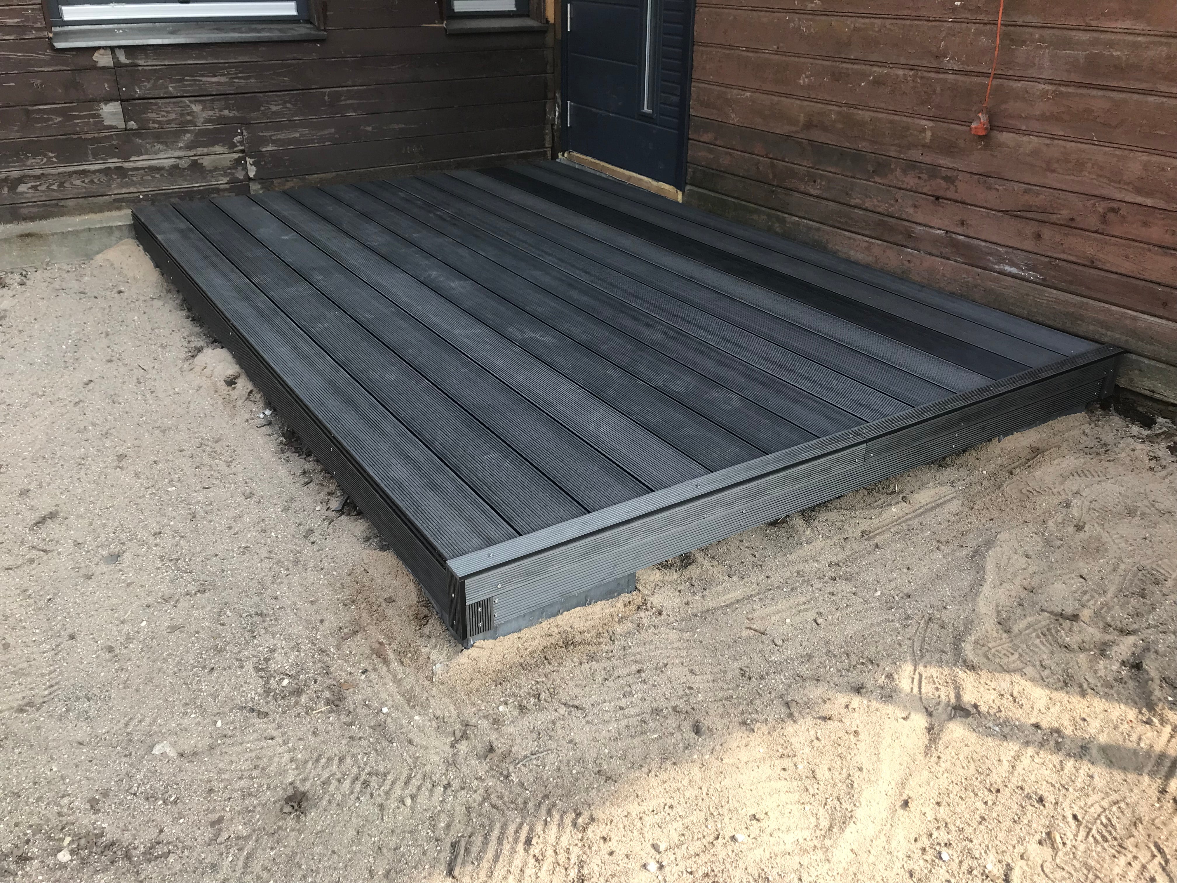 Black metal platform on a sandy ground with wooden walls in the background