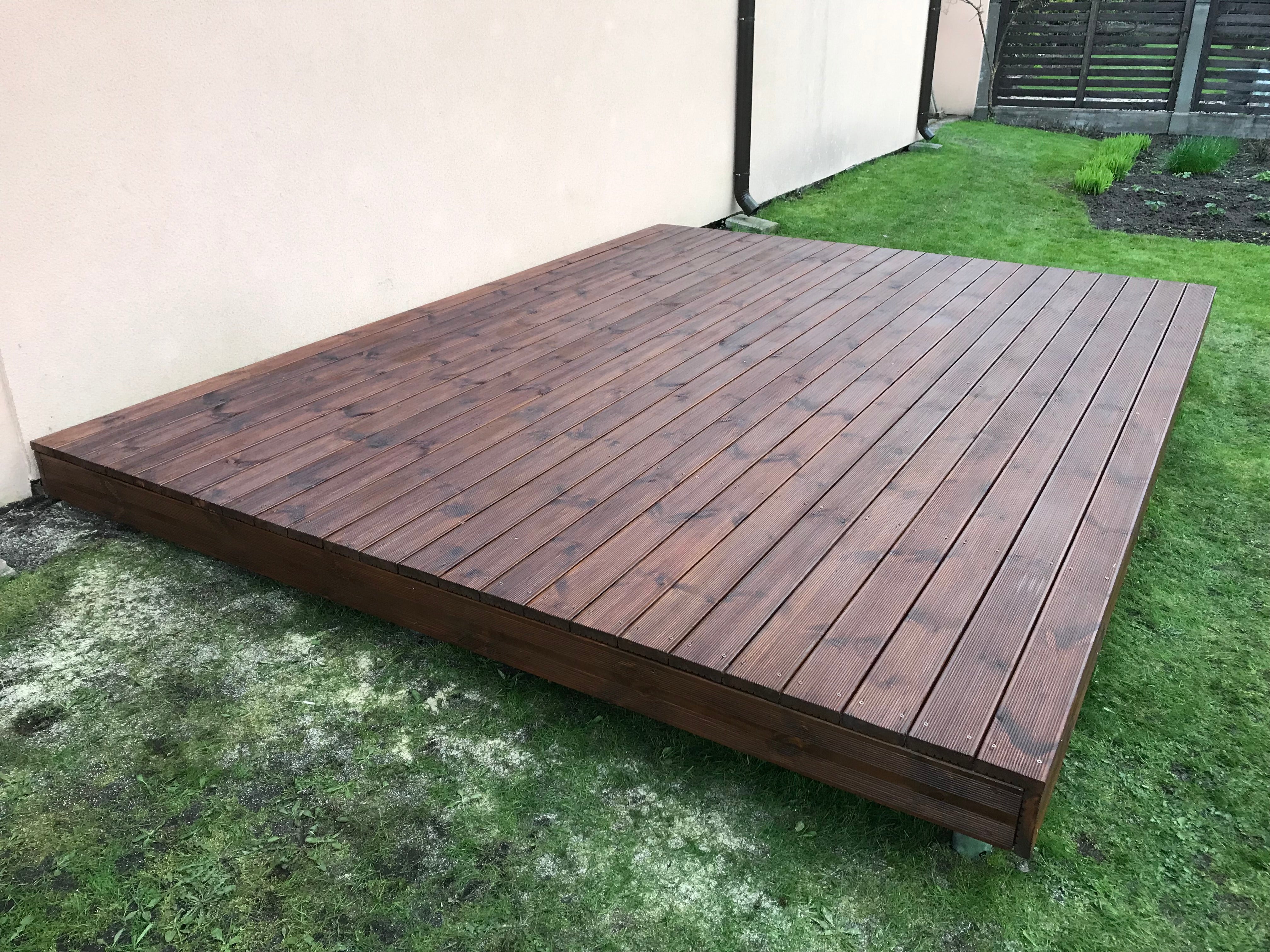 Wooden deck on grass with a neutral wall in the background
