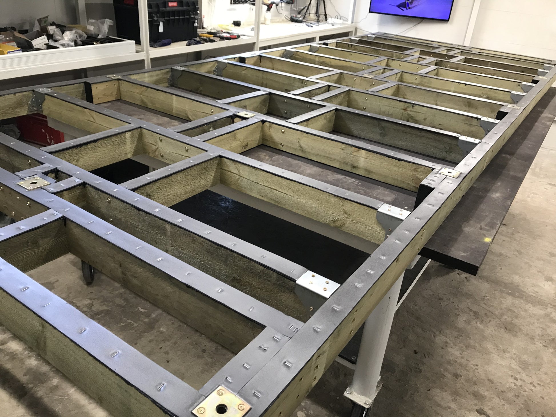 Wooden frame structure with metal reinforcements in a workshop setting