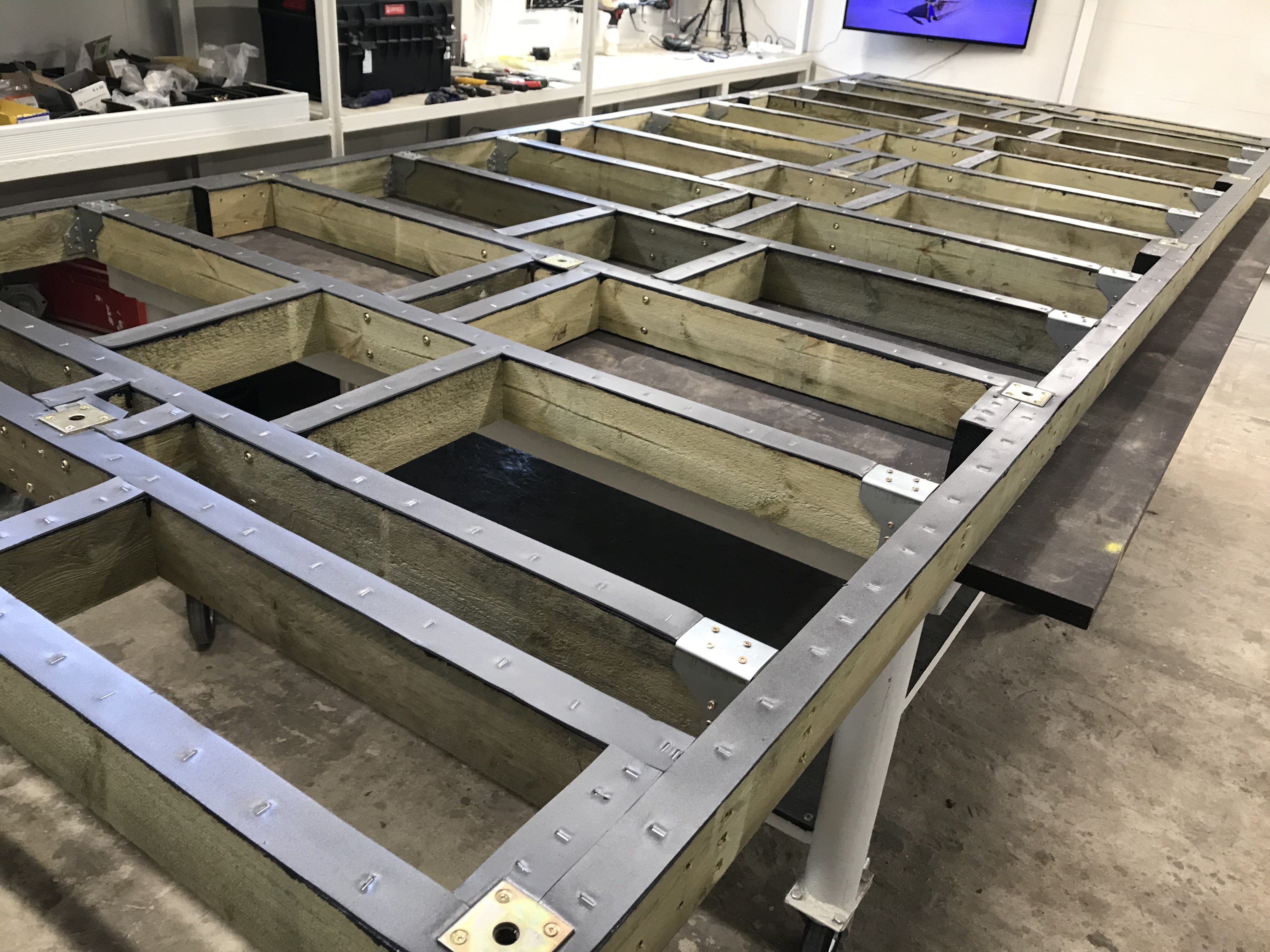 Wooden frame structure with metal reinforcements in a workshop setting