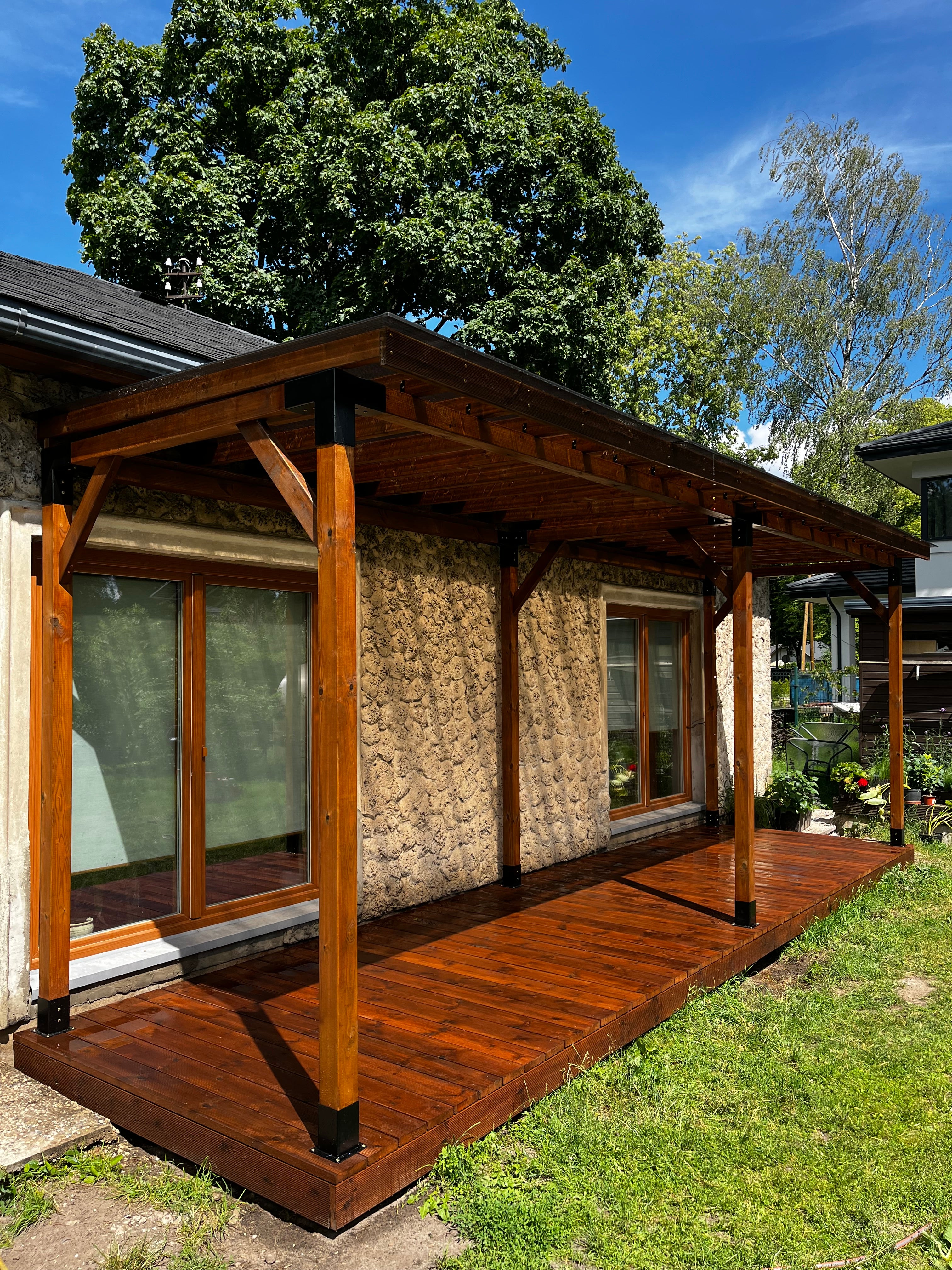 Wooden deck with glass panels and a bench, surrounded by greenery