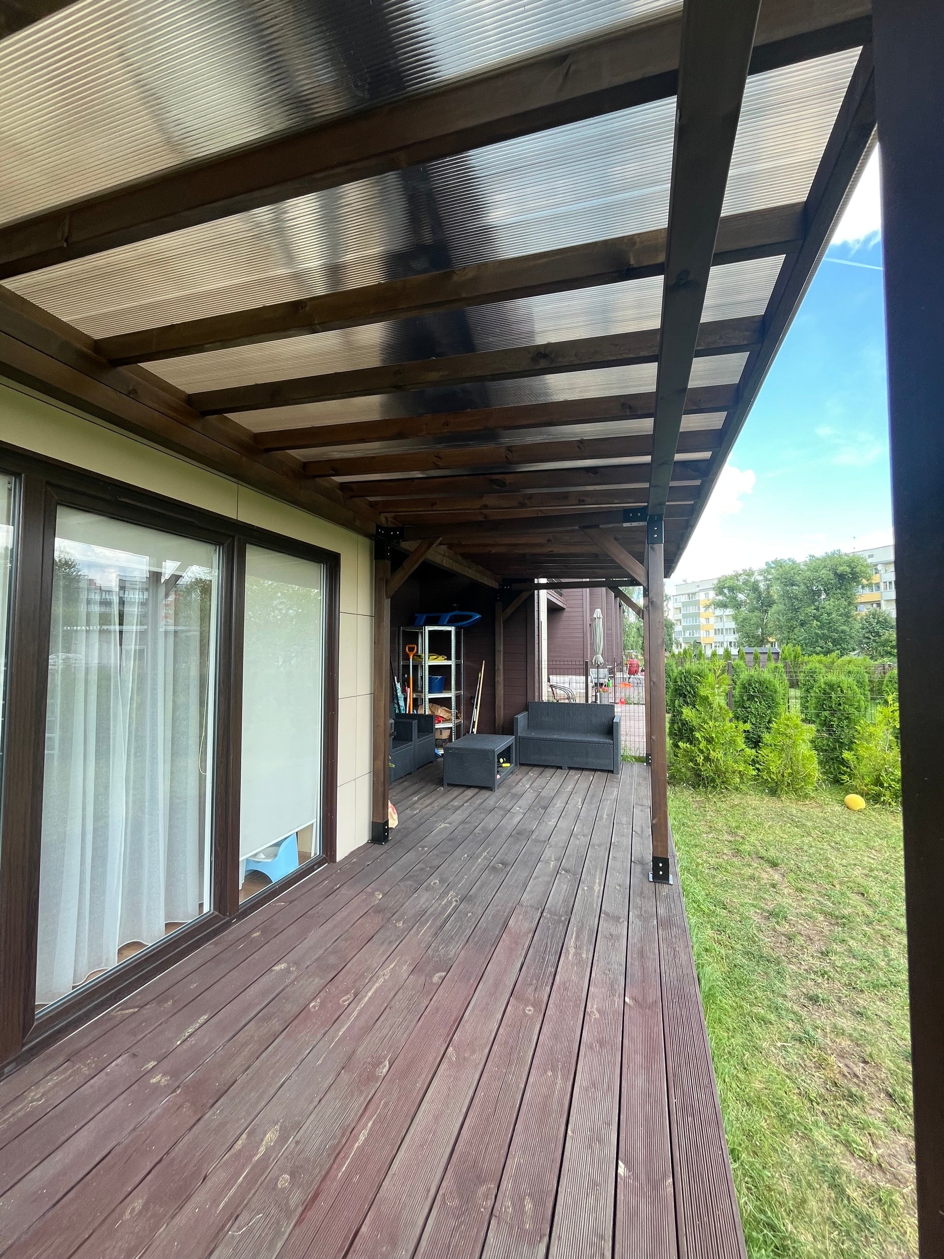 Balcony with wooden deck and railing, overlooking a grassy area.