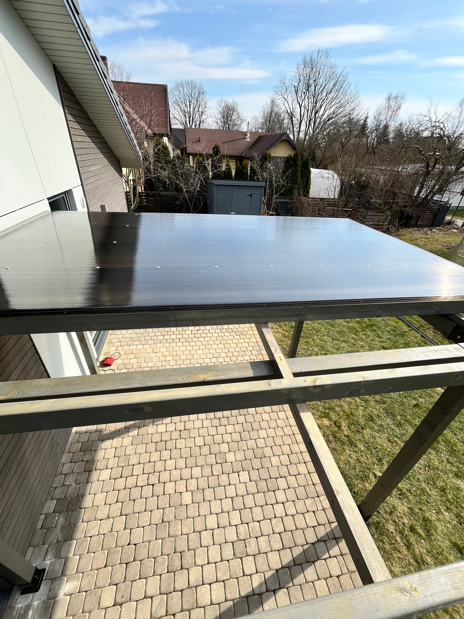 Outdoor view with a glass door or window, showing a residential area with houses and trees.