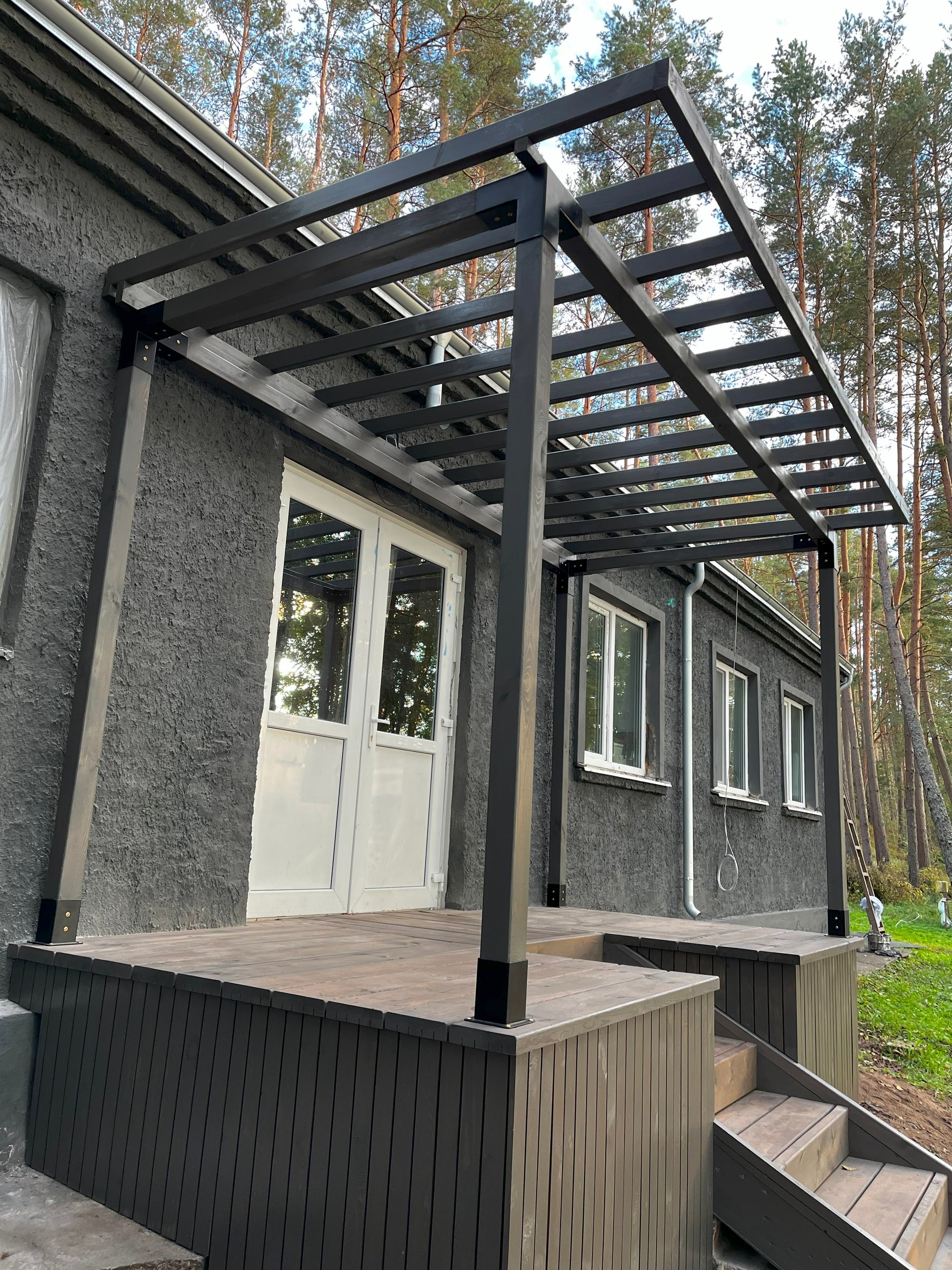 Pergola next to a house with trees in the background