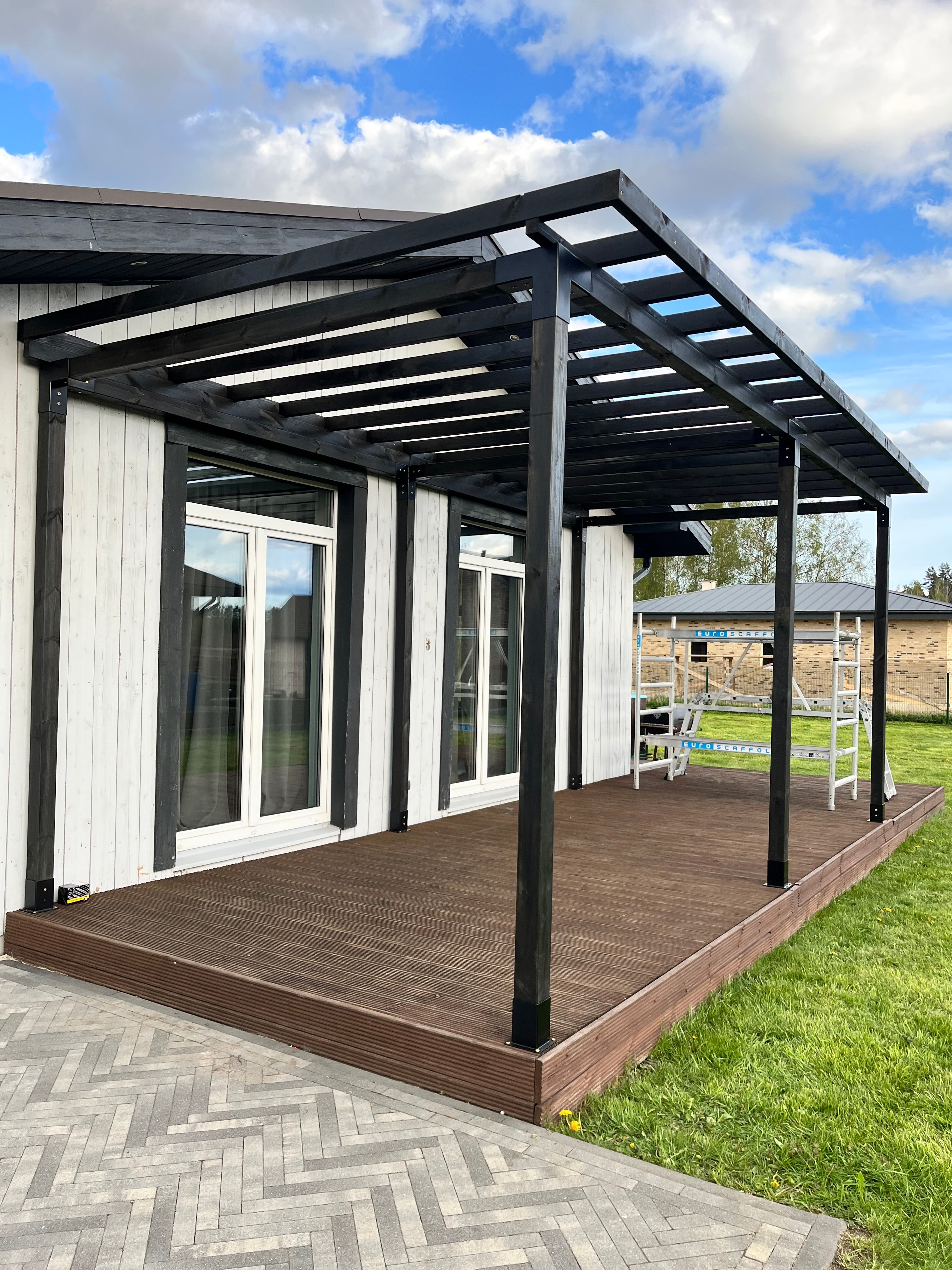 Wooden deck with black railing and glass panels on a sunny day.