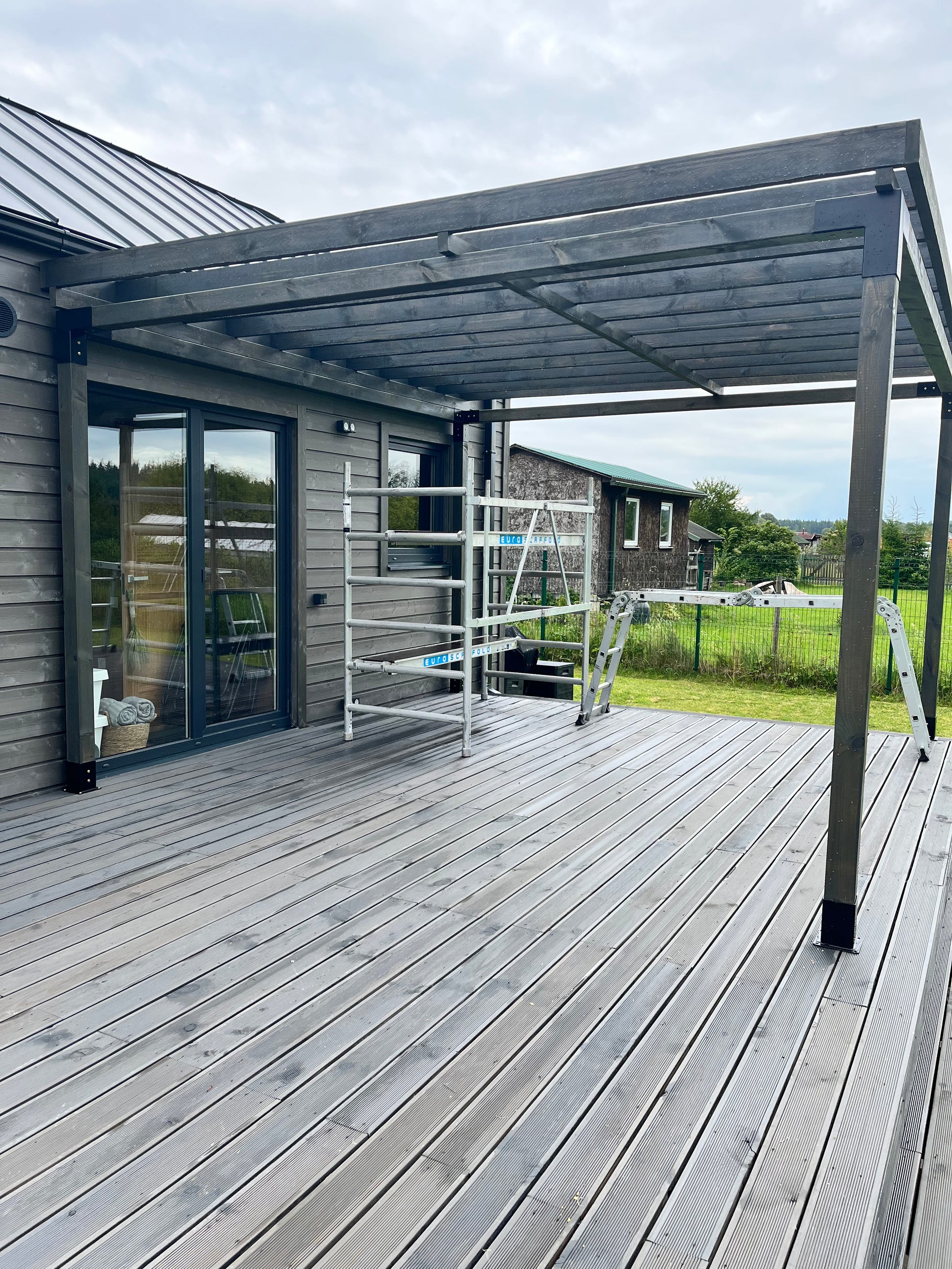 Wooden deck with glass panels and metal railings on a cloudy day