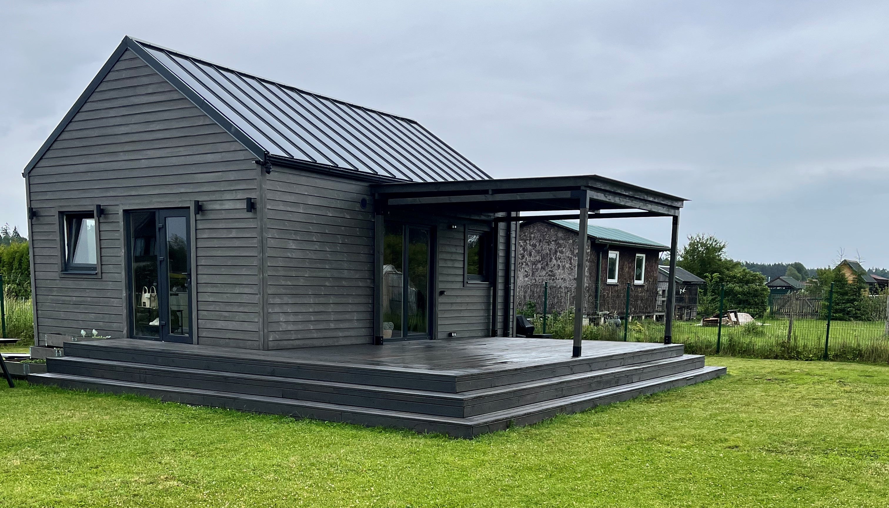 Modern house with a metal roof and wooden exterior on a grassy lawn.