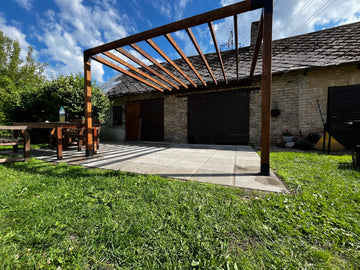 Outdoor patio area with a wooden pergola, table, and chairs in a backyard setting.