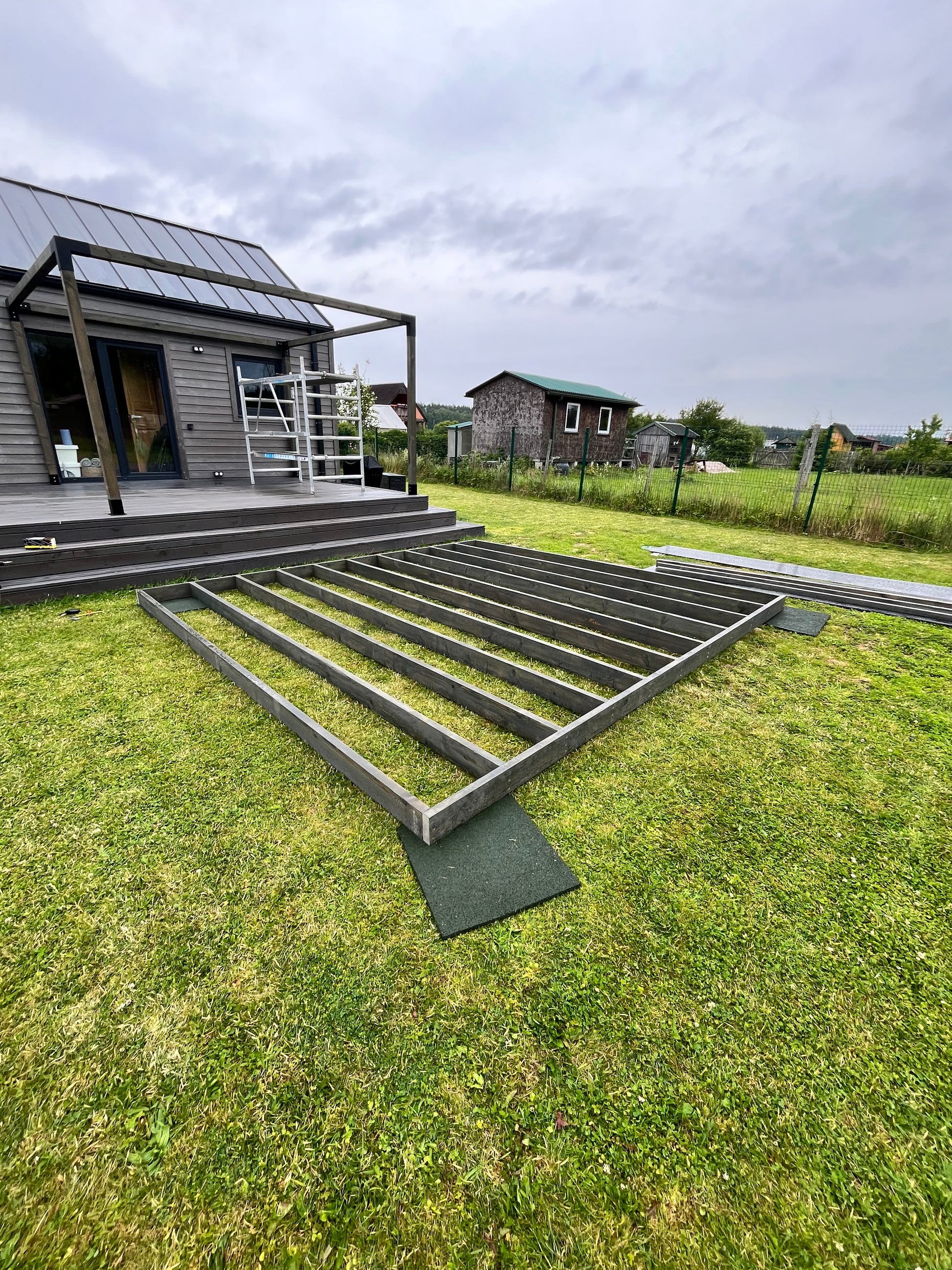 Metal staircase leading up to a house with a cloudy sky and grassy area.