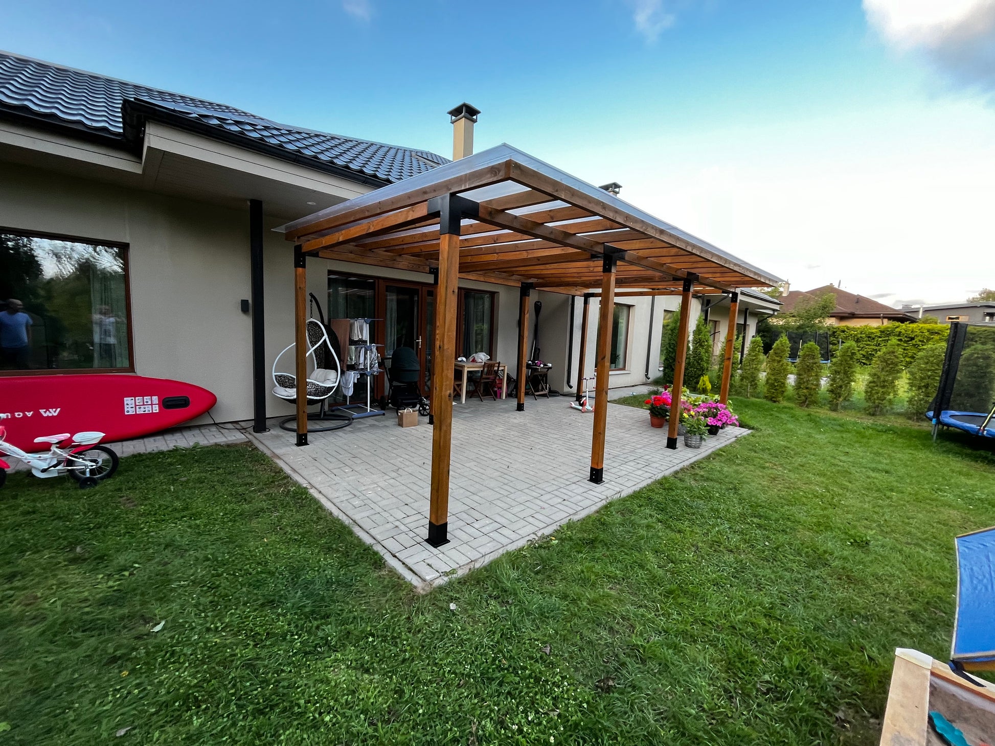 Patio area with wooden pergola, outdoor furniture, and garden decorations.