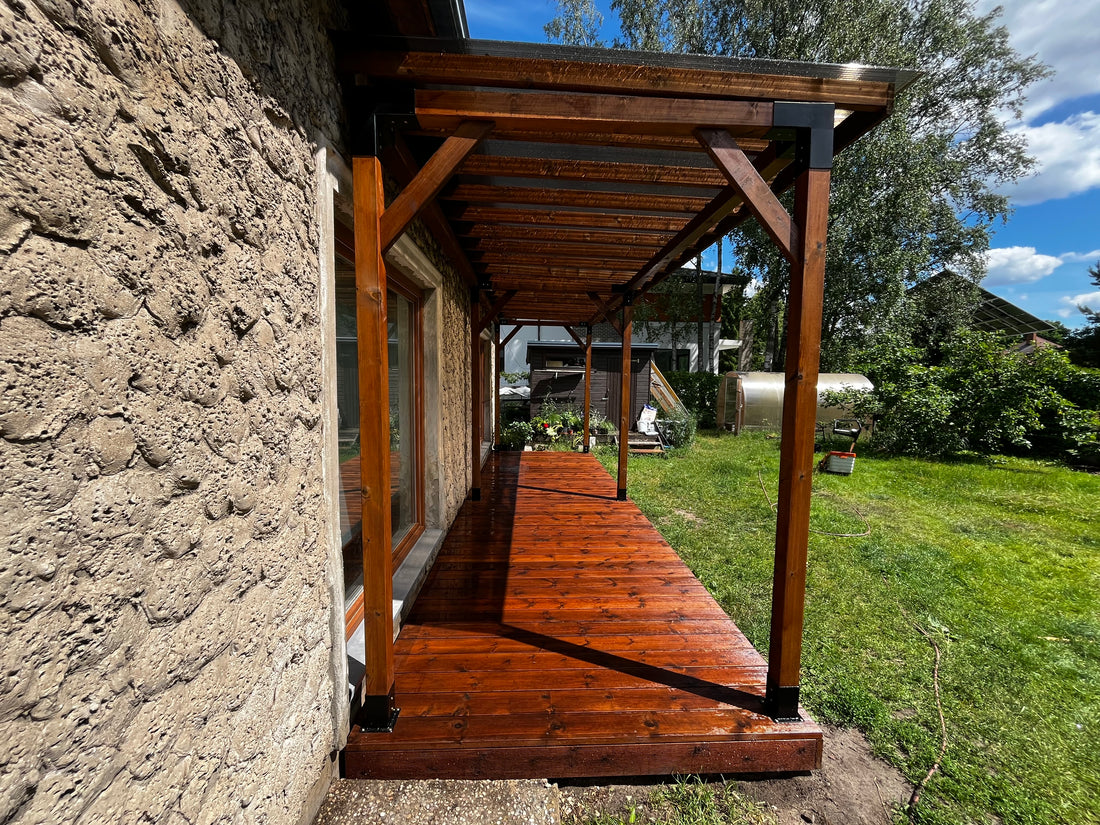 Wooden deck with glass panels and a bench, surrounded by greenery