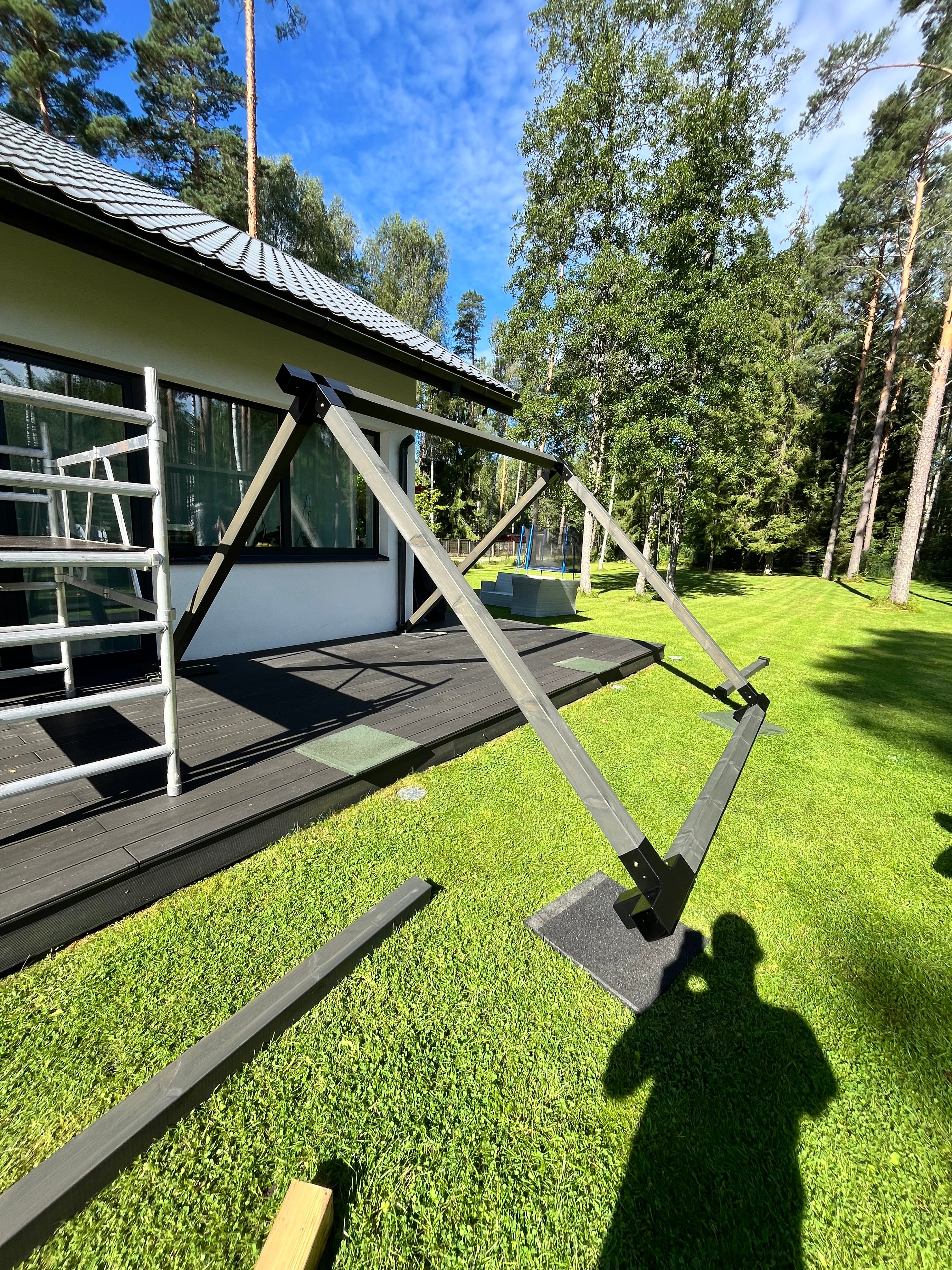 Ladder leaning against a modern building with trees and grass in the background