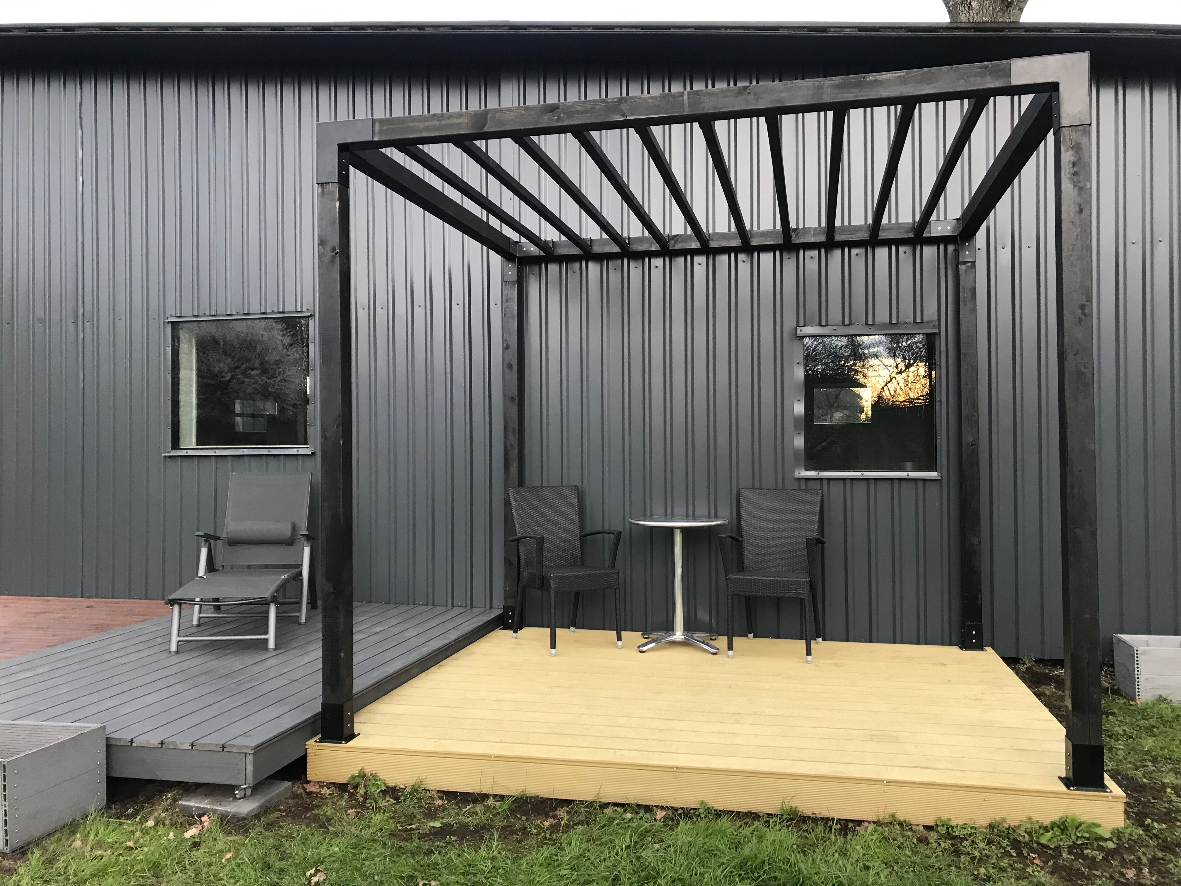 Outdoor deck with black wooden pergola and gray walls