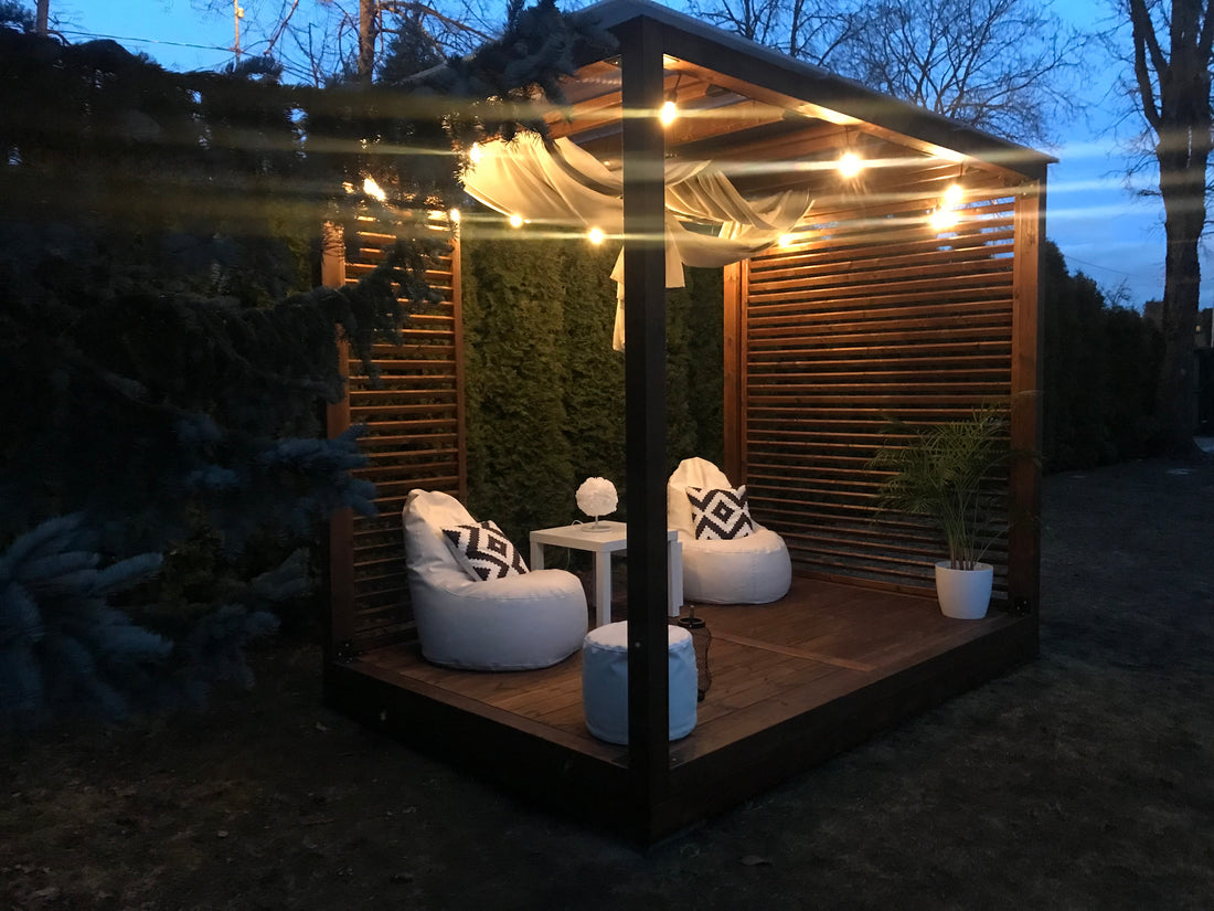 Wooden outdoor cabana with seating area and plants in a garden setting