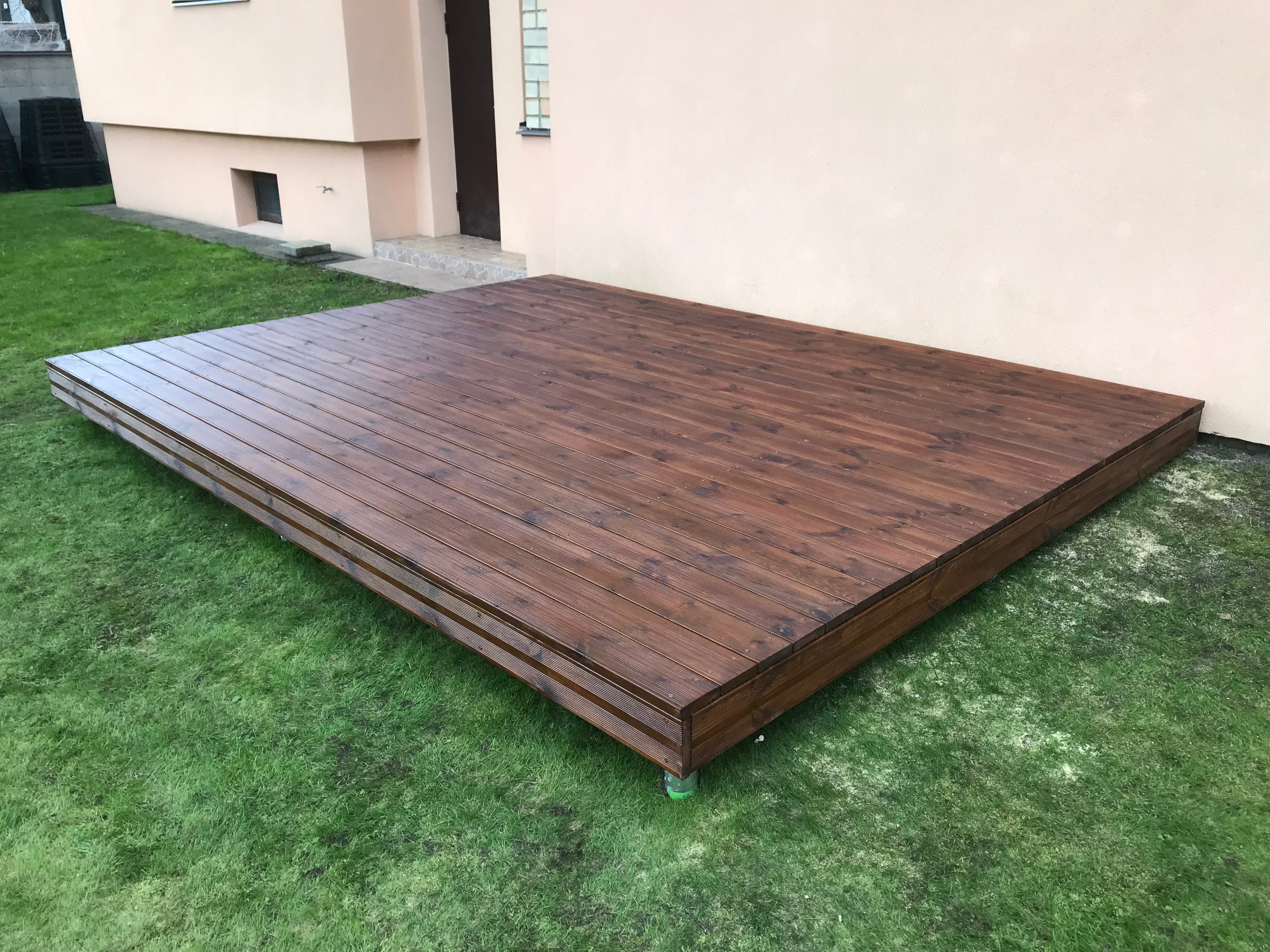 Wooden deck on grass with a building in the background