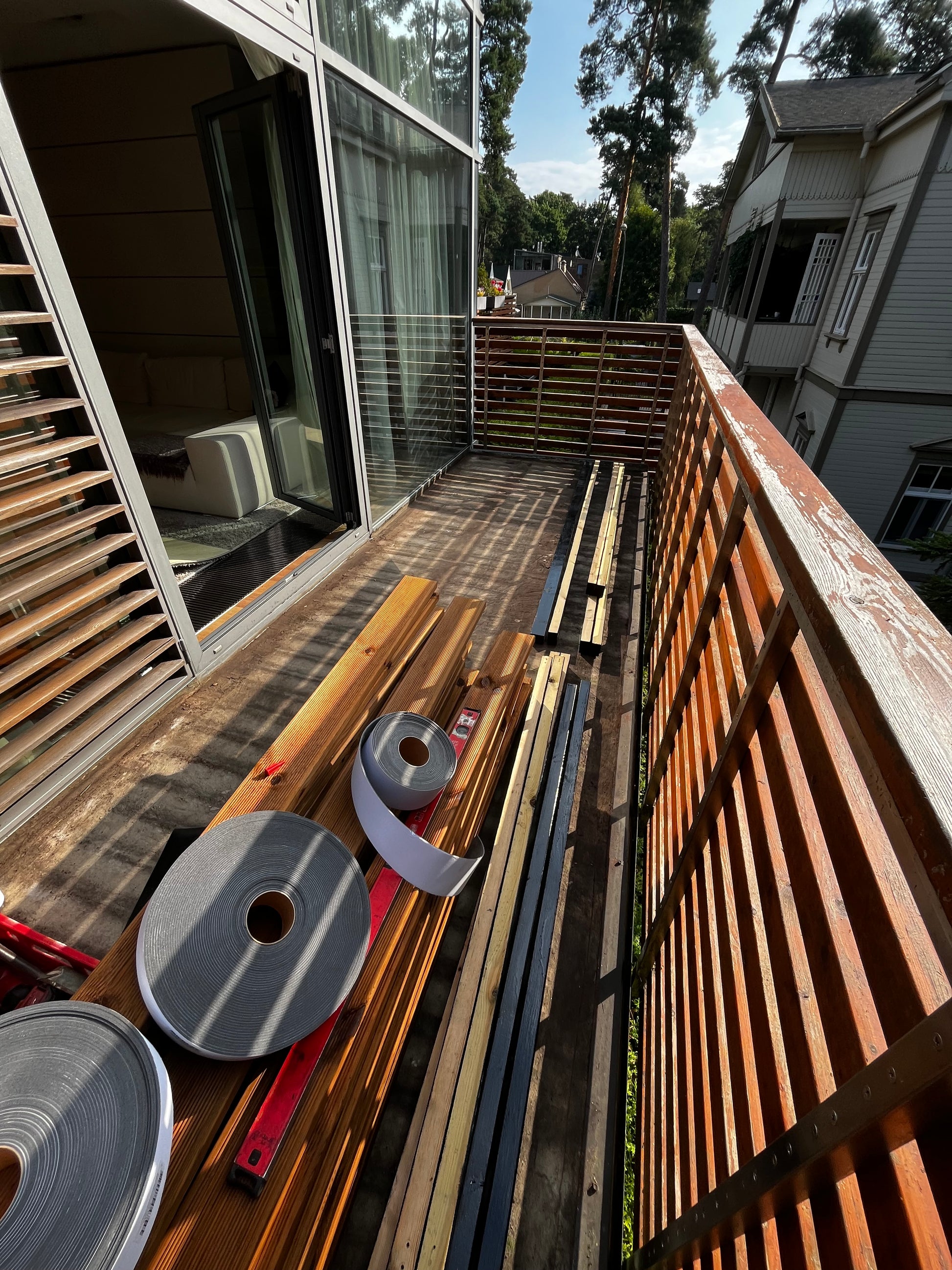 Stack of wooden planks and metal rolls on a balcony with a building in the background