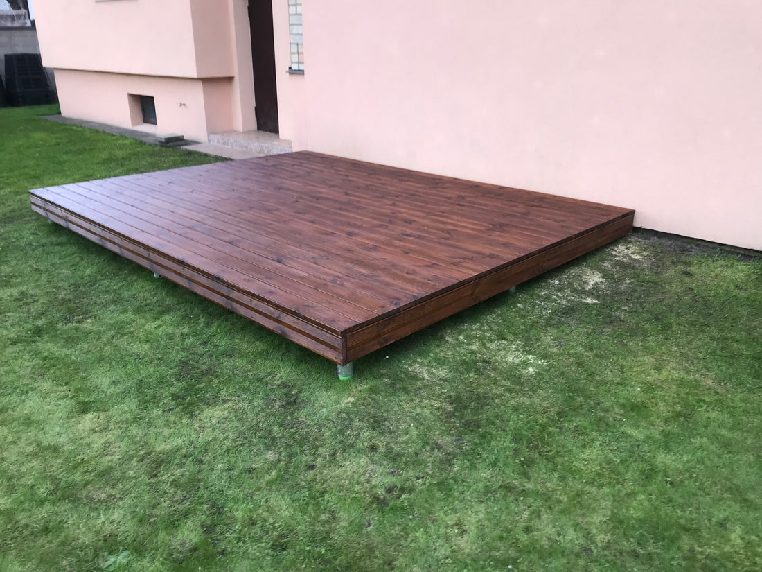 Wooden deck on grass with a white wall background
