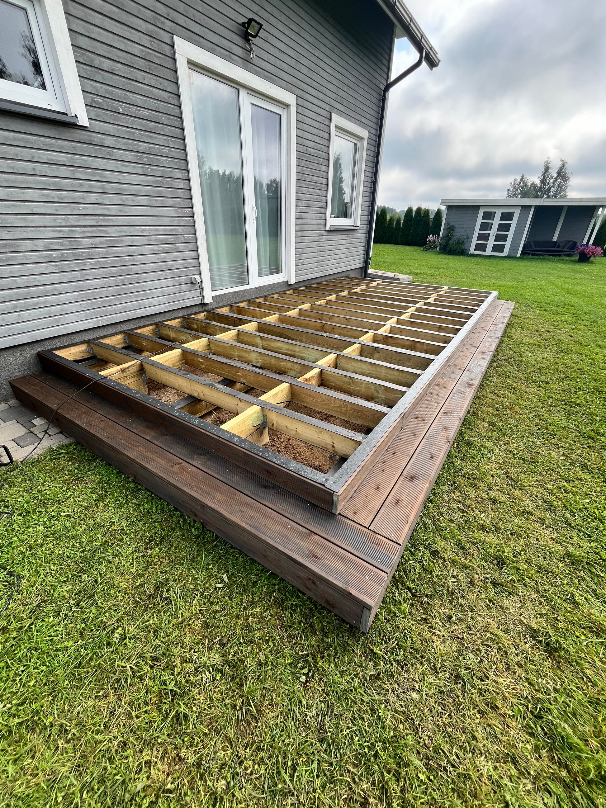 Wooden deck structure on grass next to a house