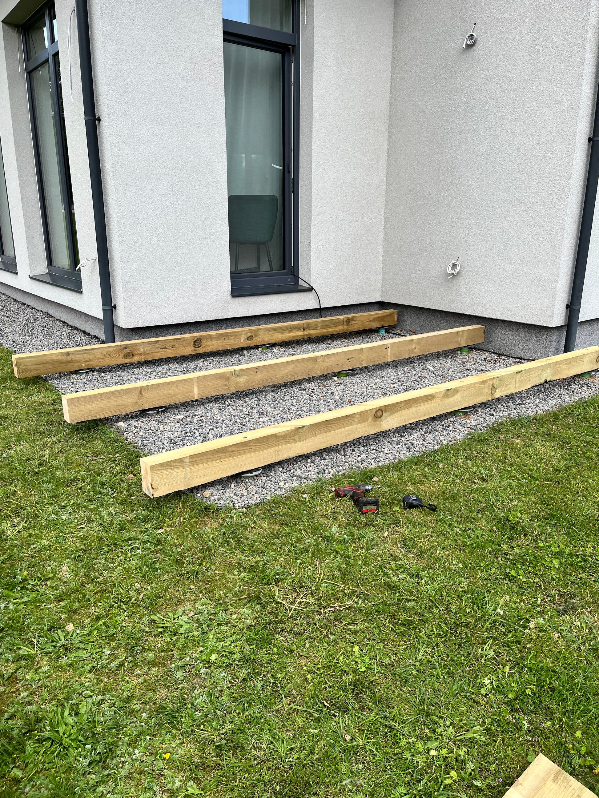 Wooden planks leaning against a building with tools on the ground