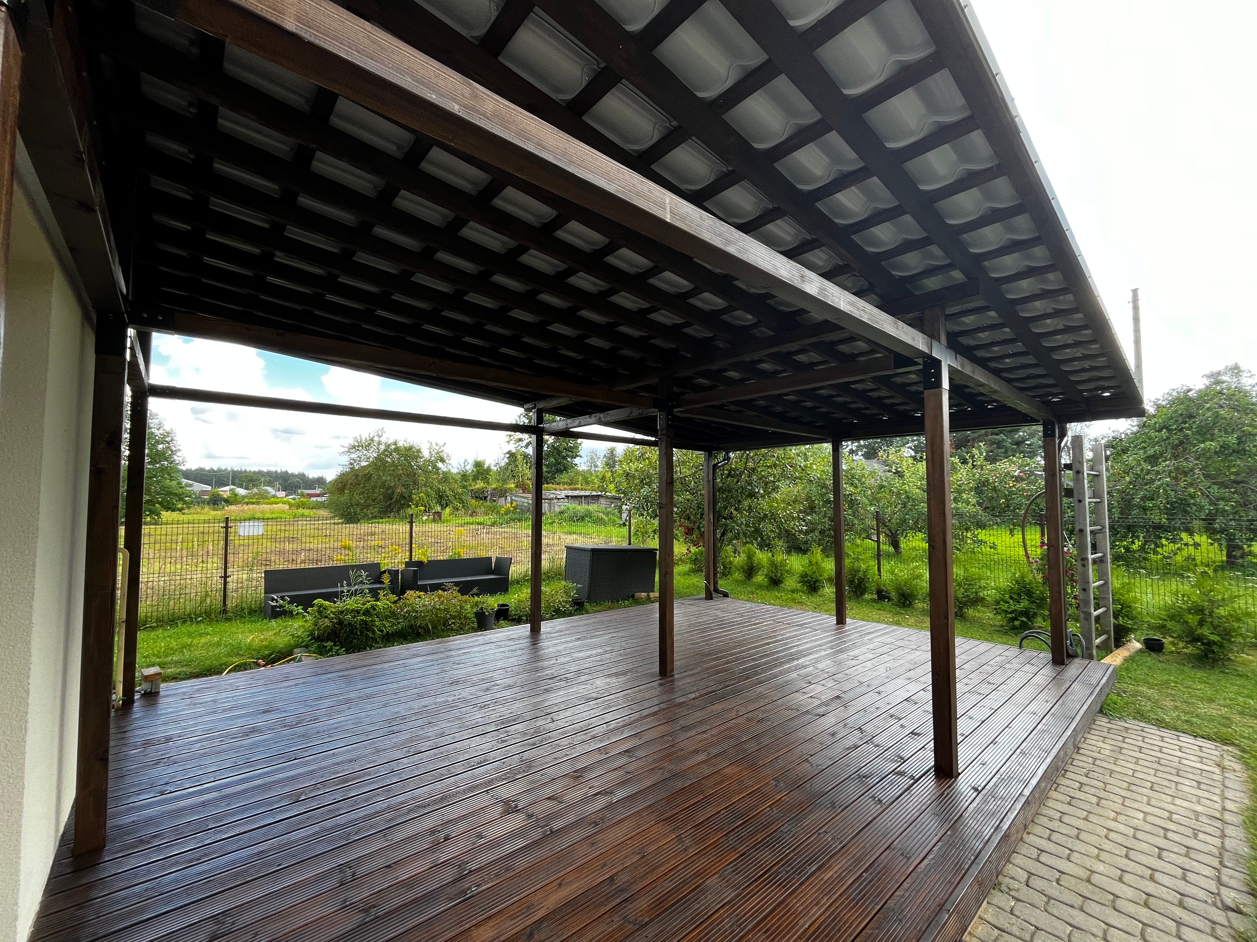 Wooden deck with a roofed area overlooking a grassy field