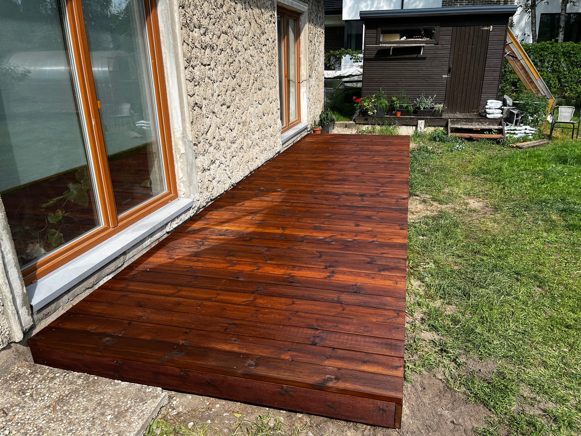 Wooden deck extending from a house with a grassy area in the background