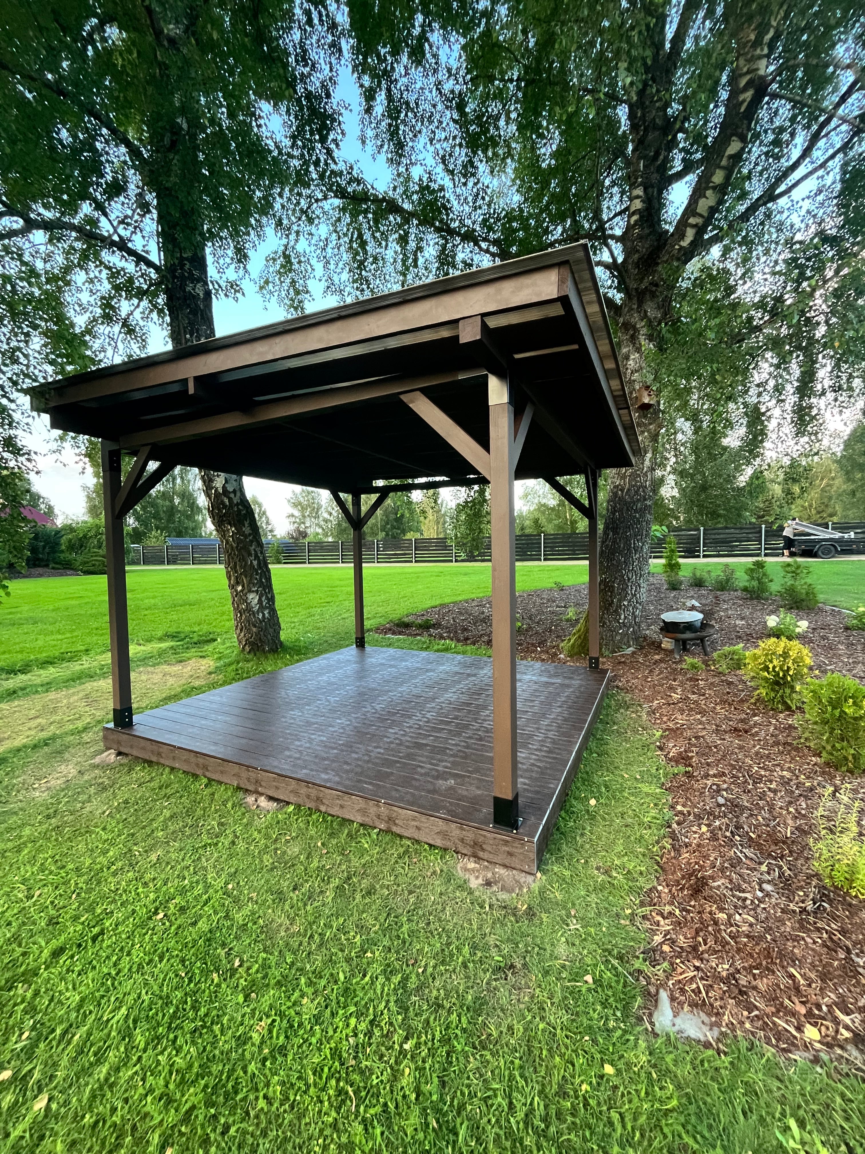 Wooden gazebo in a grassy area with trees in the background