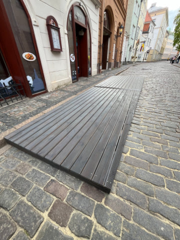 Wooden terrace deck next to restaurant entrance on a cobblestone street