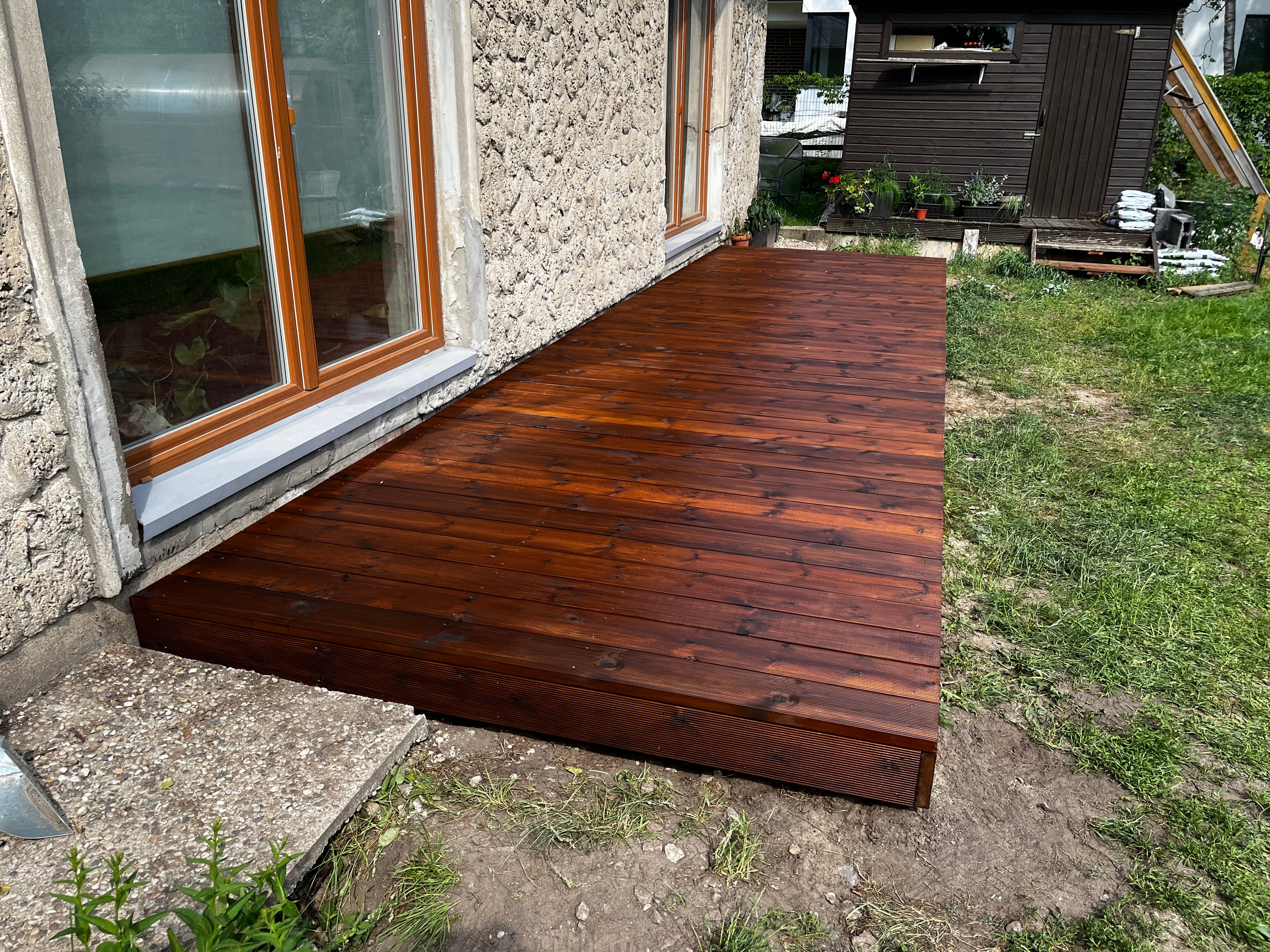 Wooden deck extension attached to a house with stone exterior