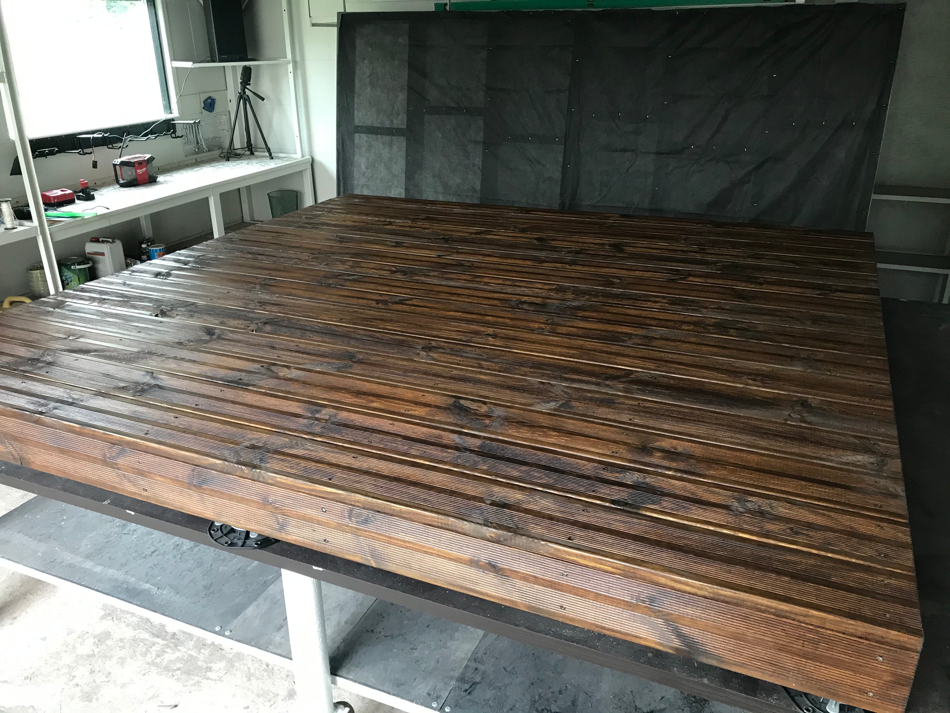 Wooden panel with a dark finish on a stand, with a blurred background of a room.