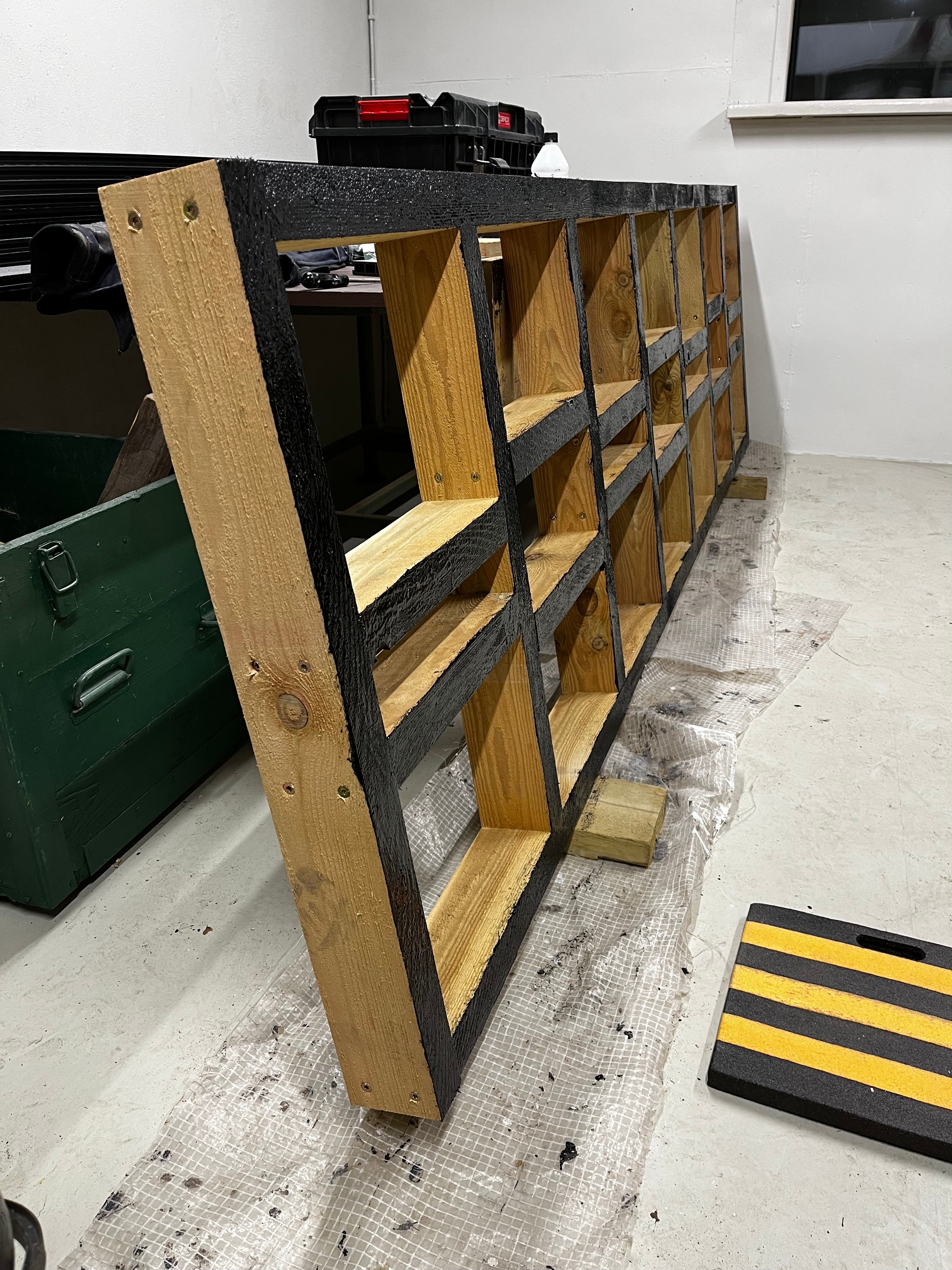 Wooden storage shelf with black border on a concrete floor.