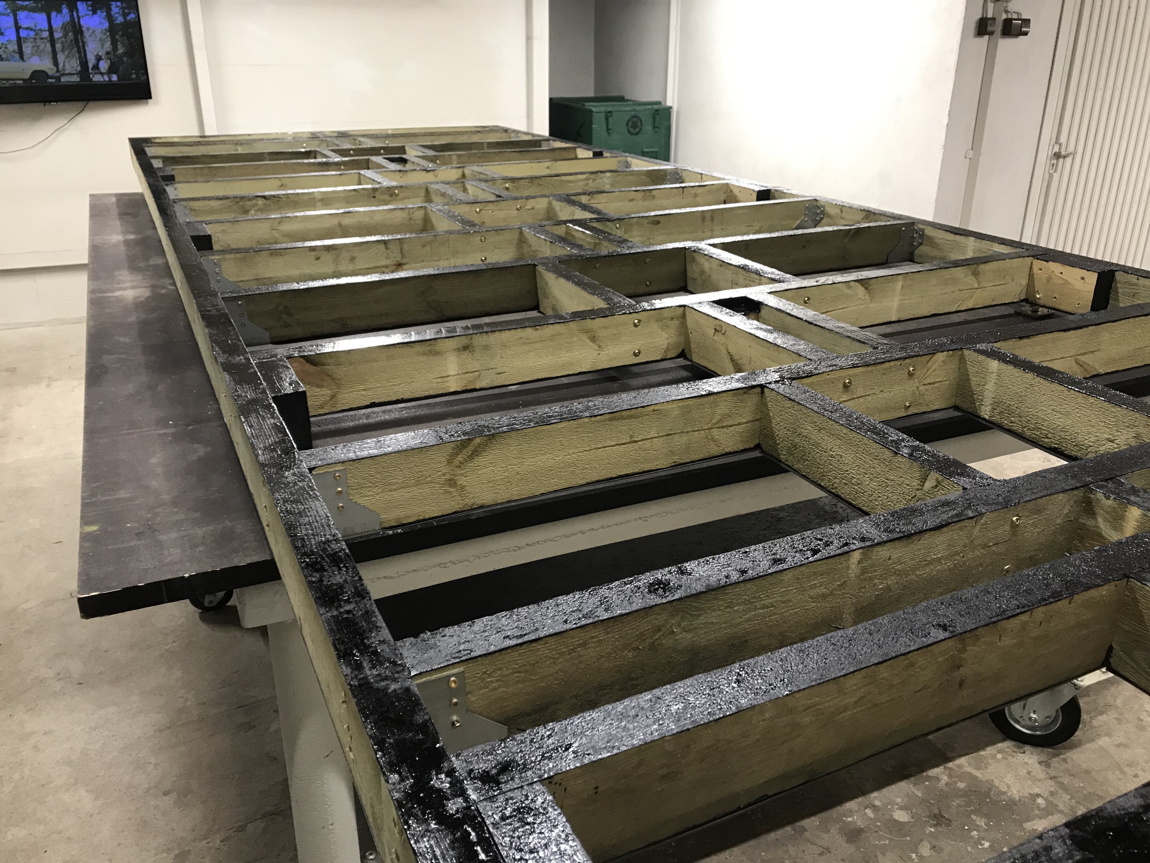 Wooden frame structure on a metal platform in an indoor setting