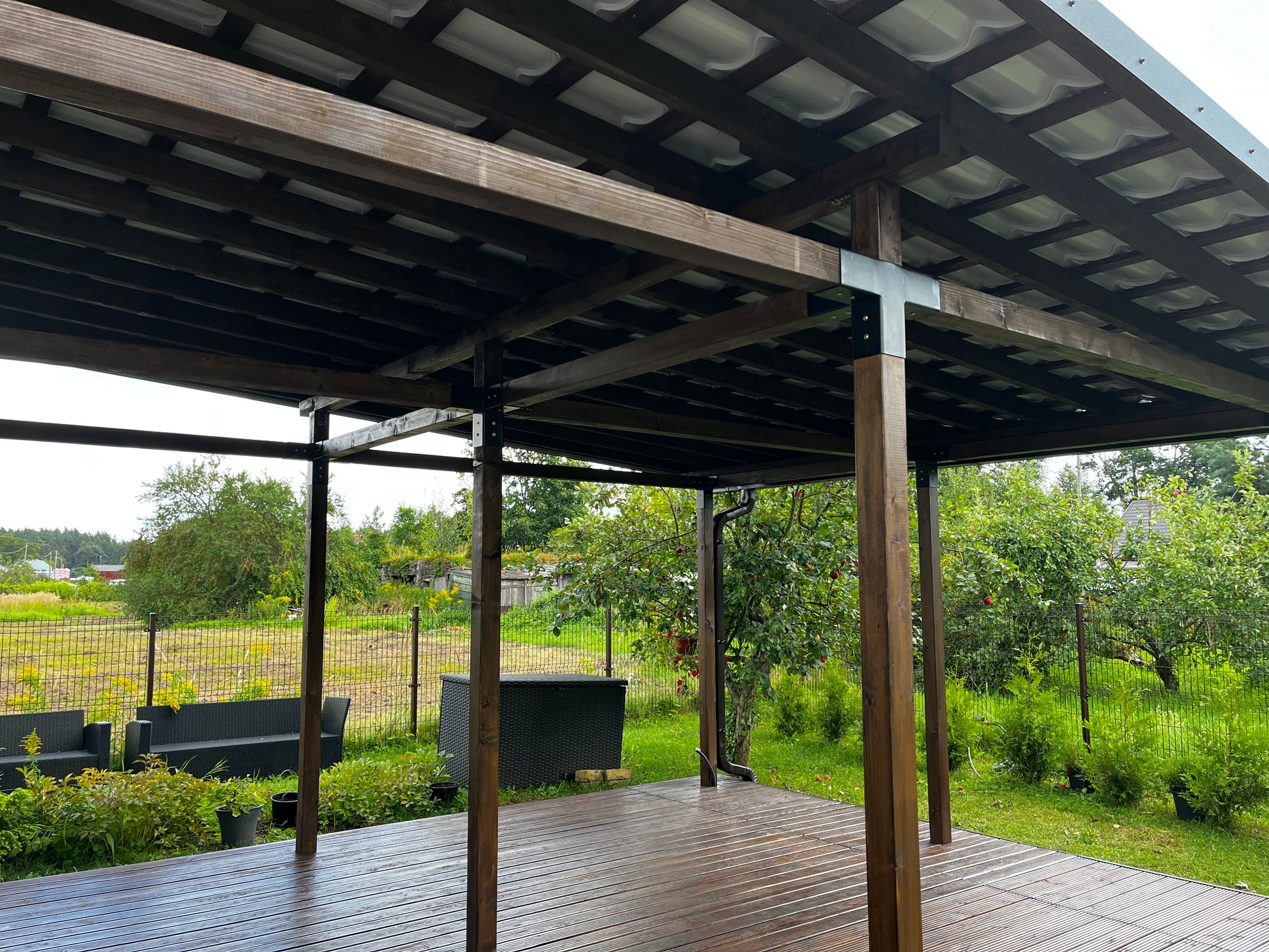 Wooden deck with a pergola structure overlooking a green landscape.