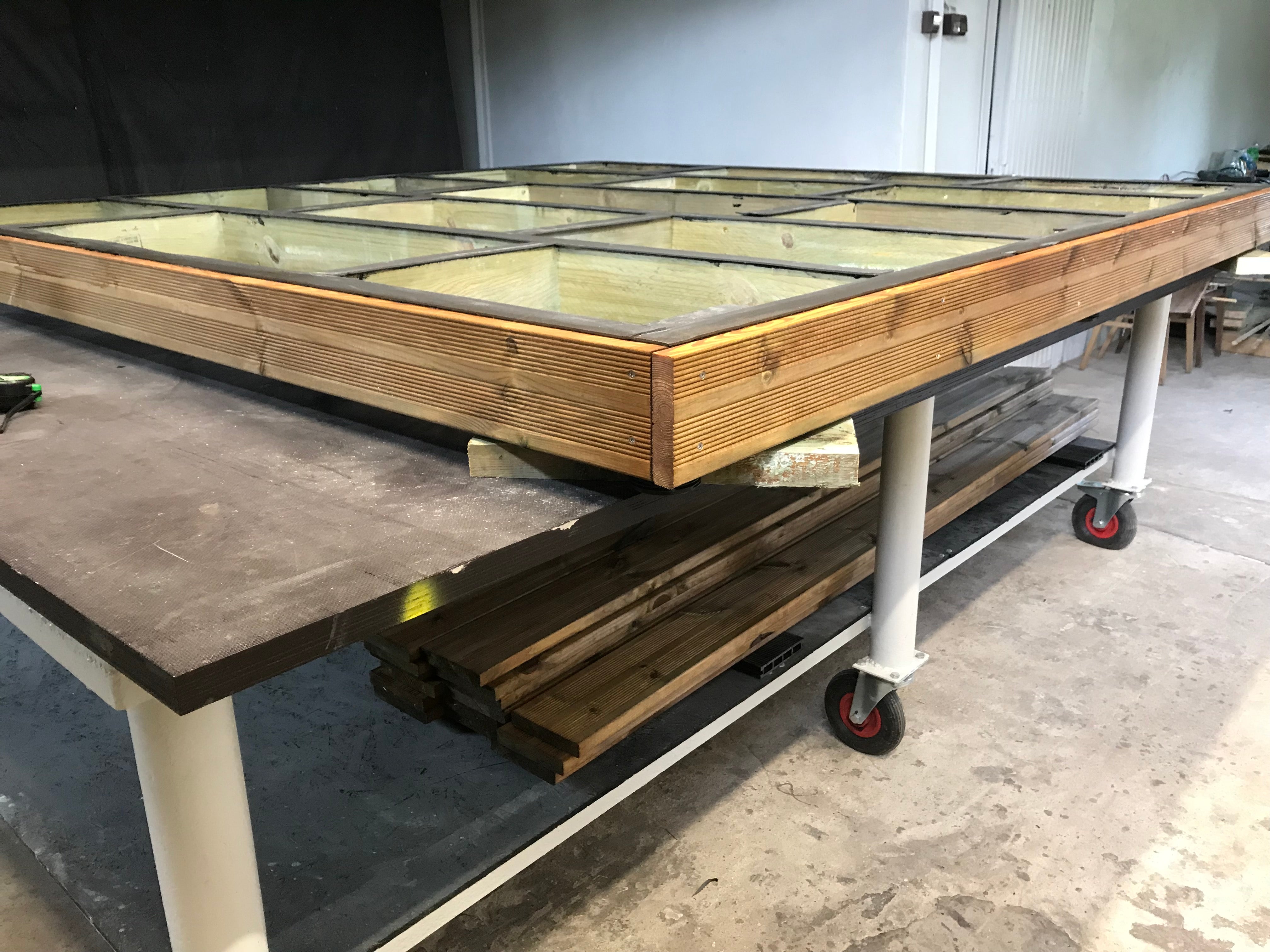 Wooden frame on a metal cart with glass panels in a workshop setting