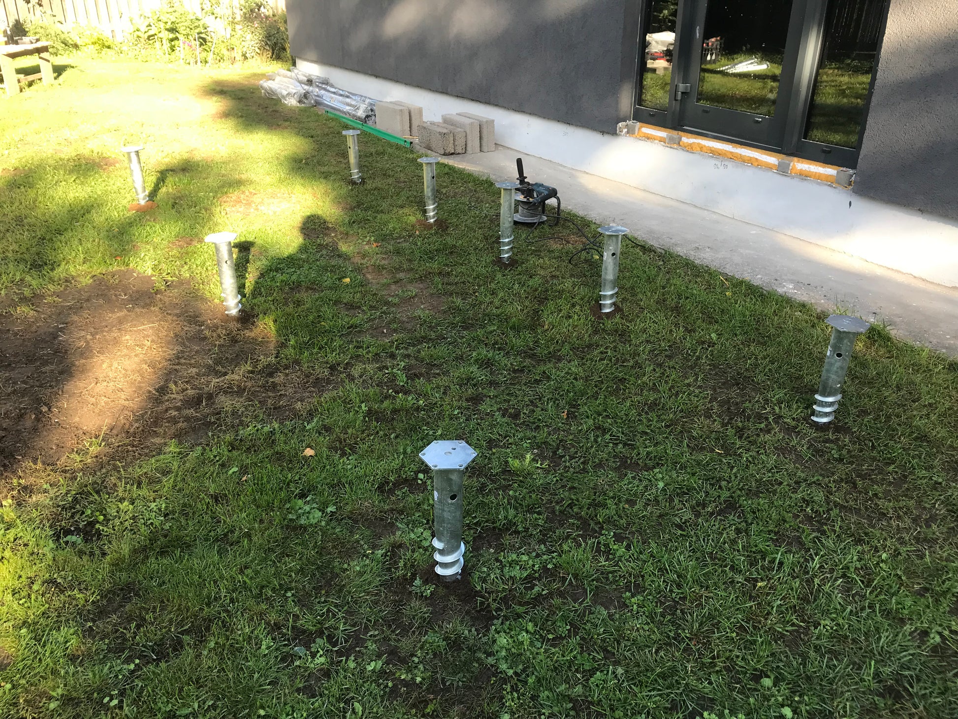 Foundation with metal supports on grass, possibly indicating a new construction or renovation project.