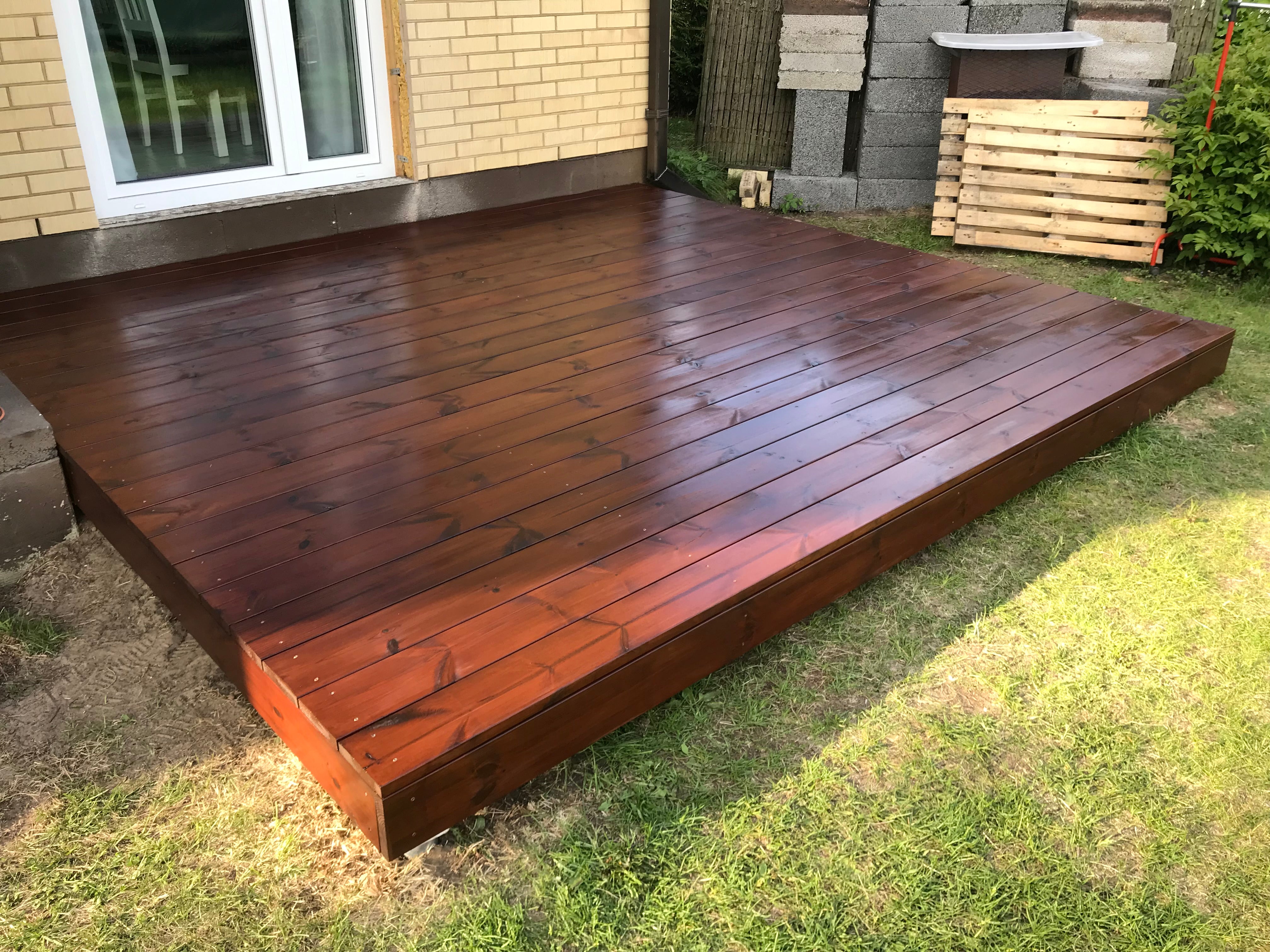 Wooden deck on a grassy area with a building in the background