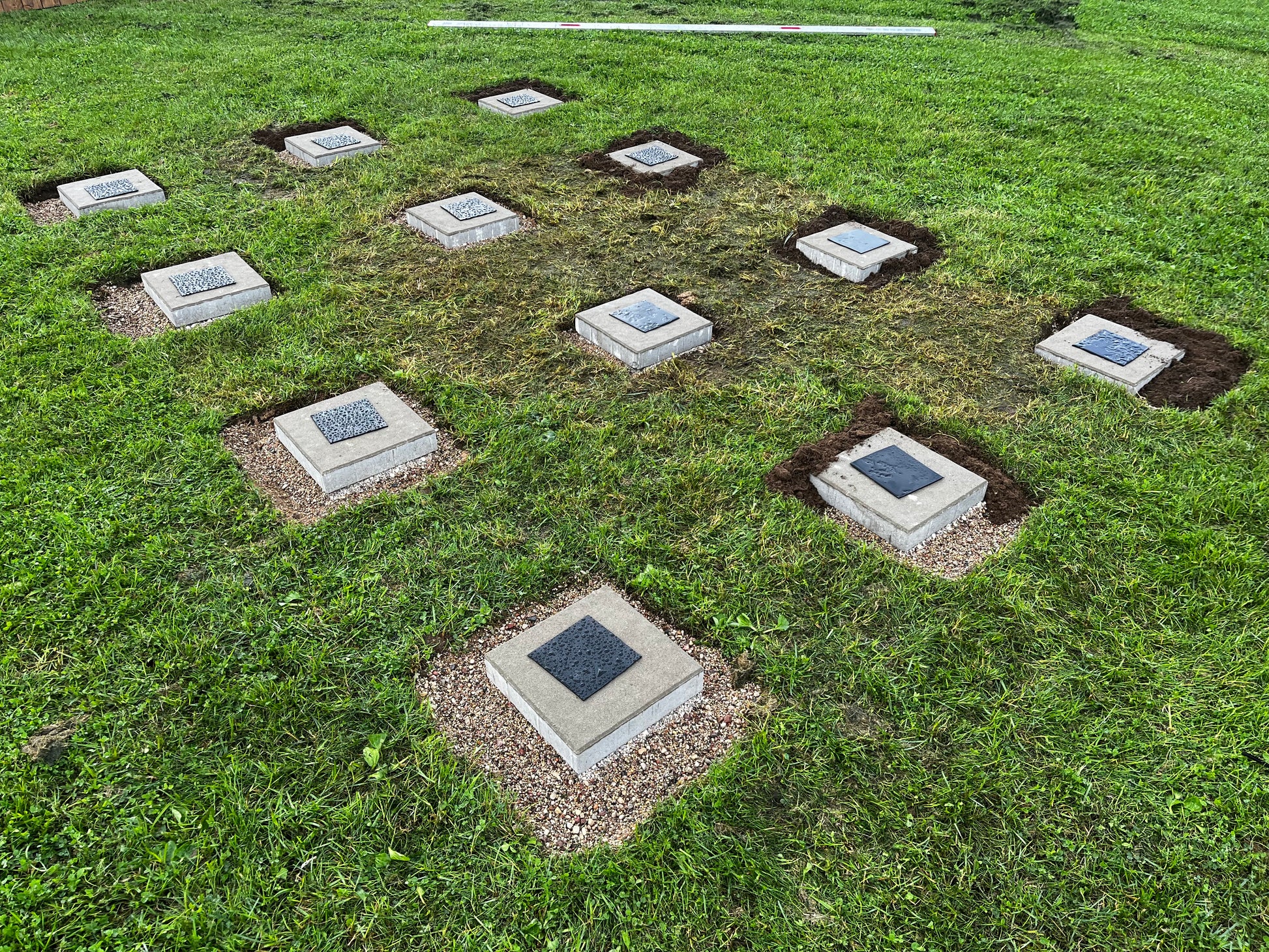 Grid of square concrete slabs embedded in grass
