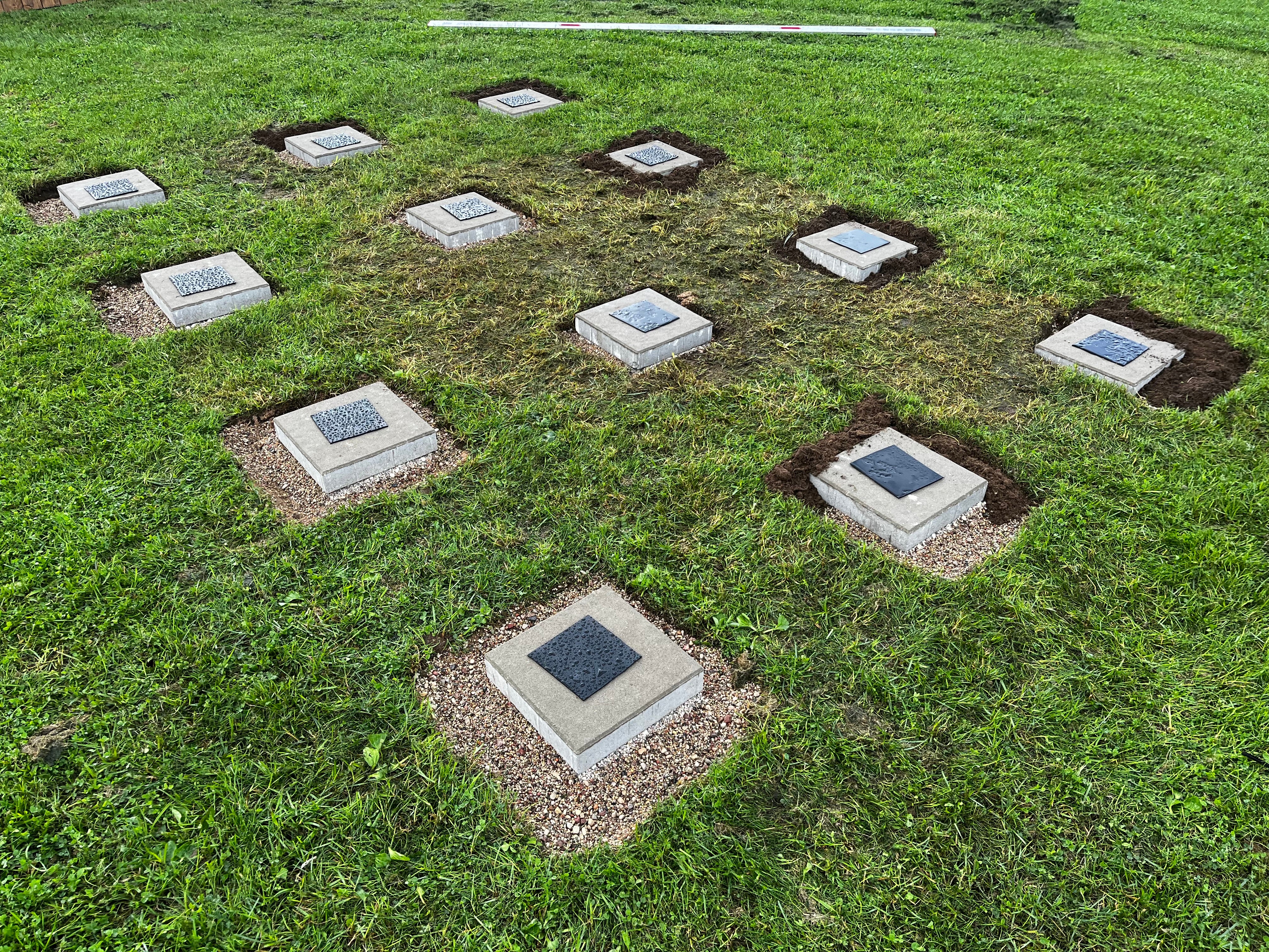 Grid of square concrete slabs embedded in grass