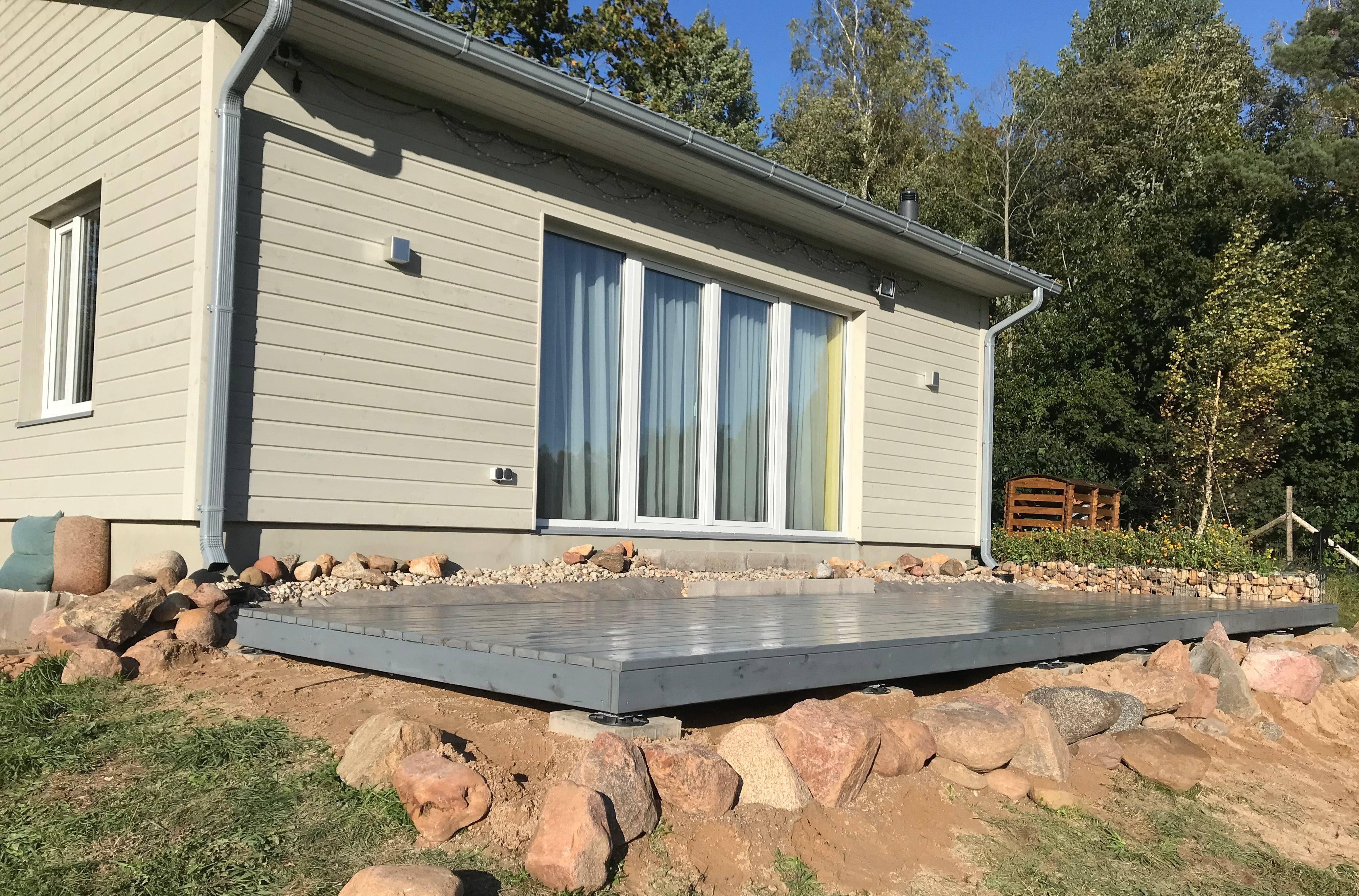 Modern house exterior with a stone patio and surrounding trees