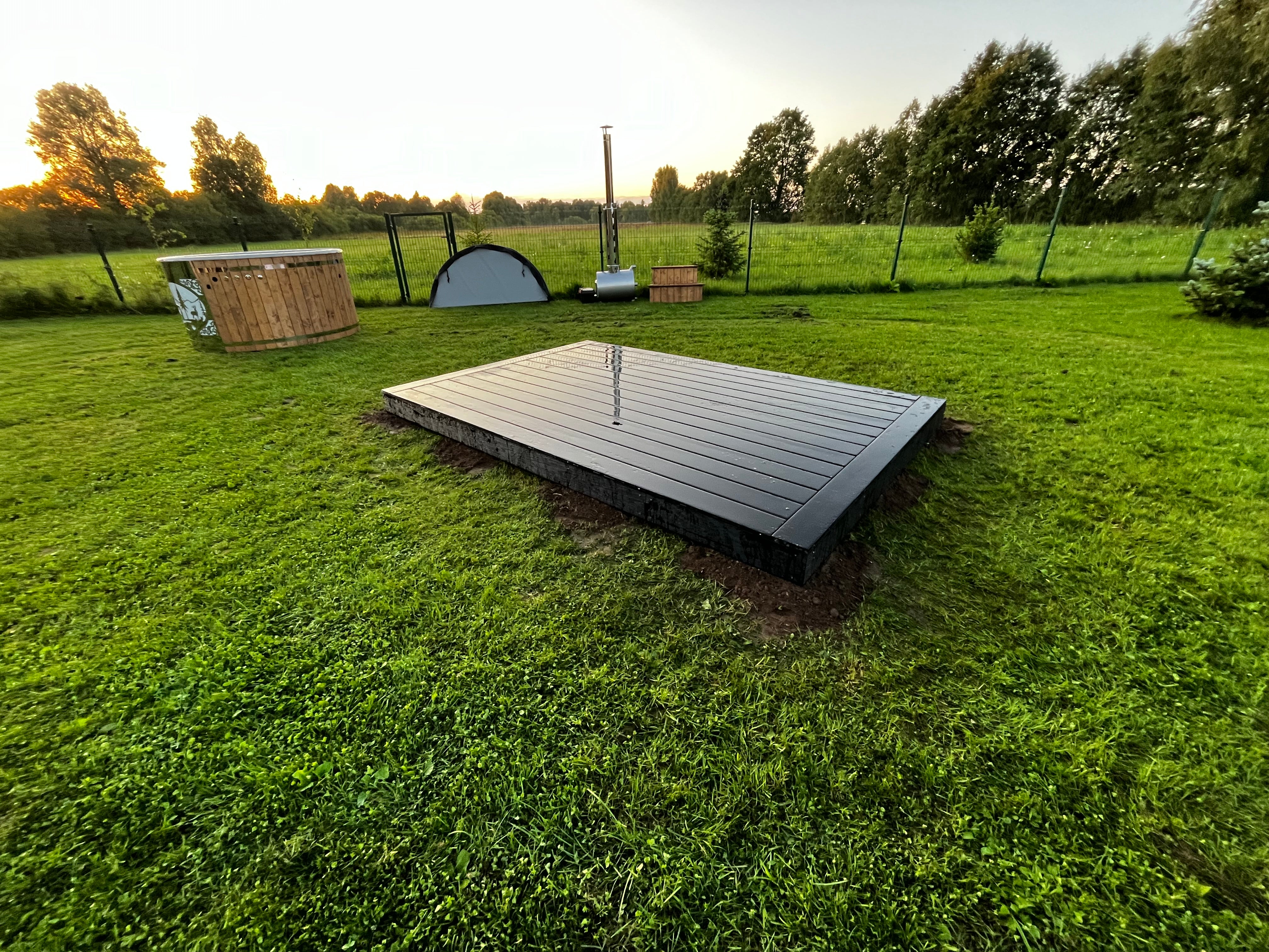 Wooden platform in a grassy outdoor area with trees in the background