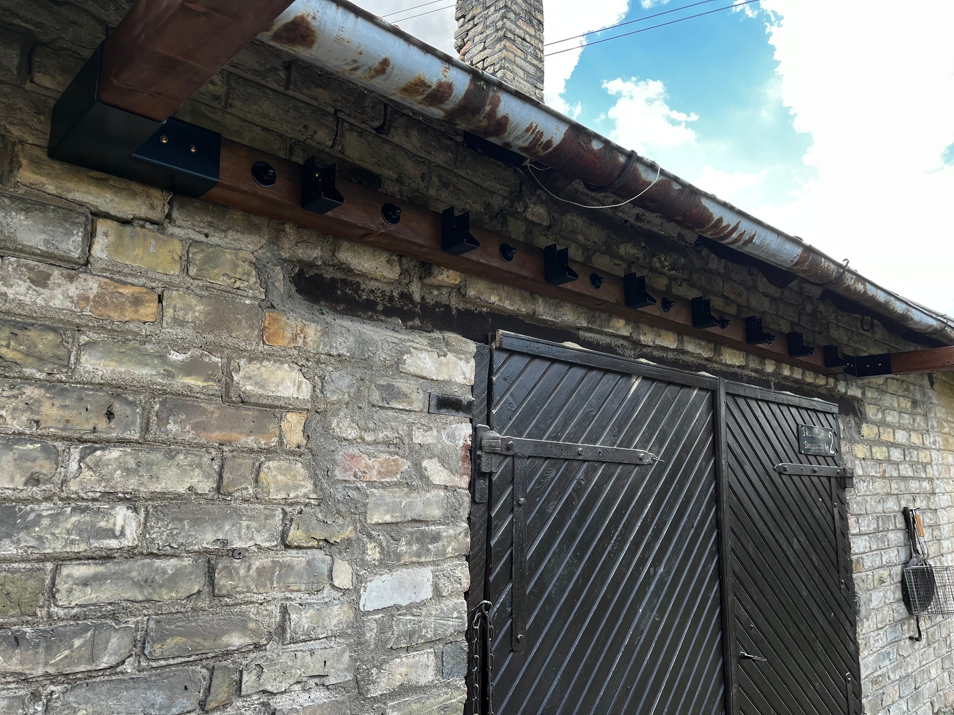 Rustic stone building with a metal door and roofline