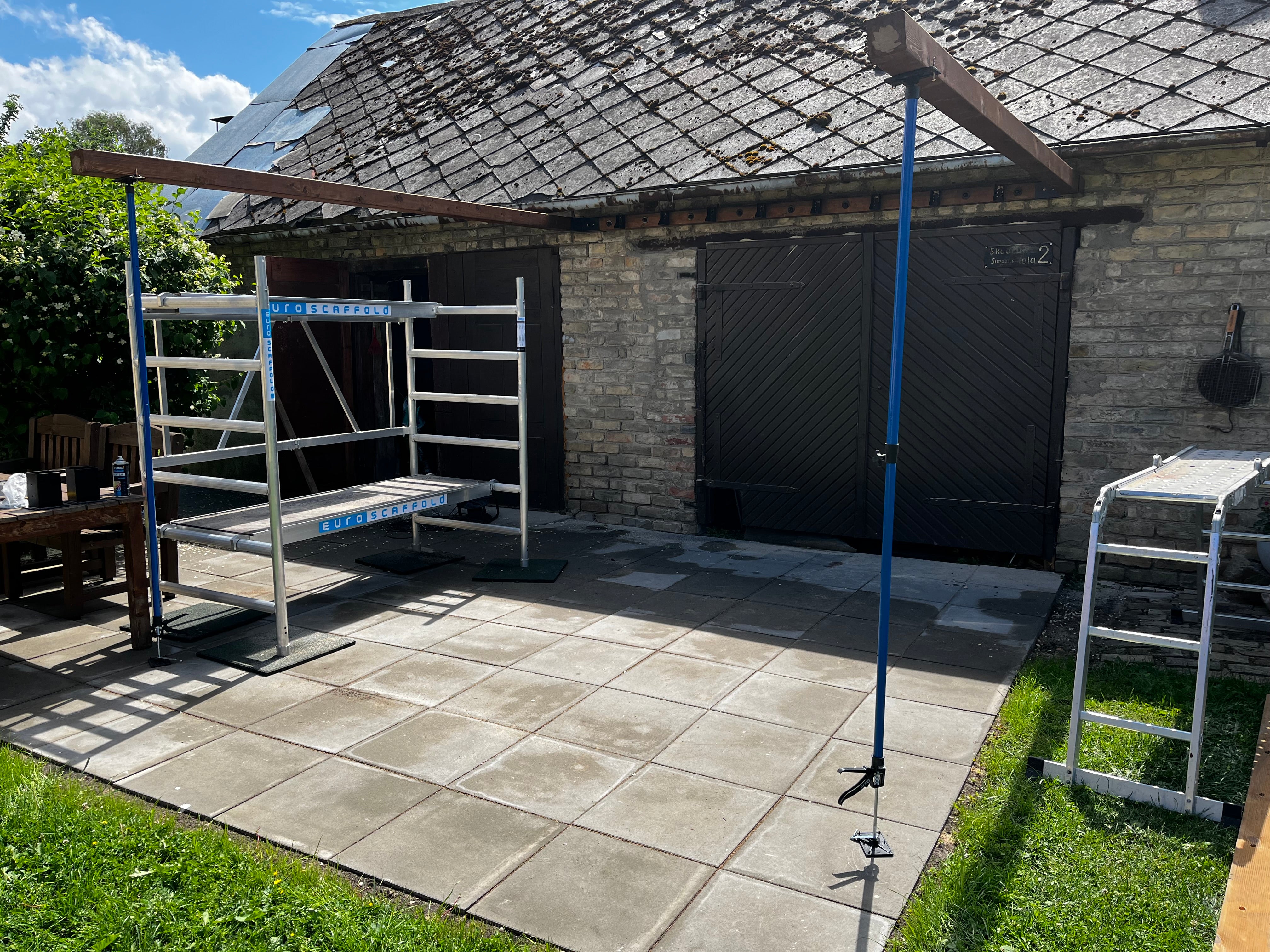 Outdoor patio area with a brick building, outdoor furniture, and a ladder.